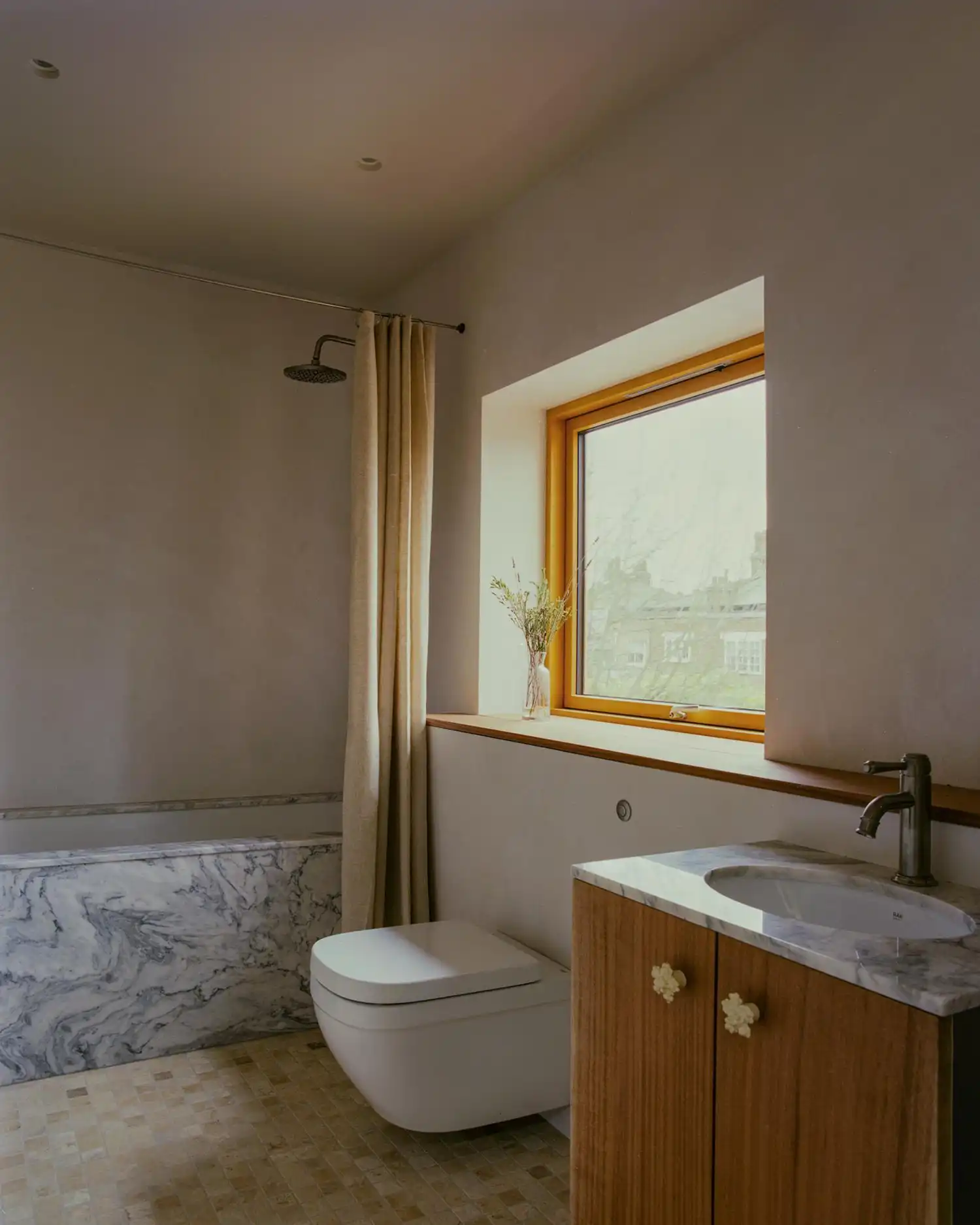 Modern bathroom in Runda house with marble tub, oak vanity, and custom ceramic knobs.