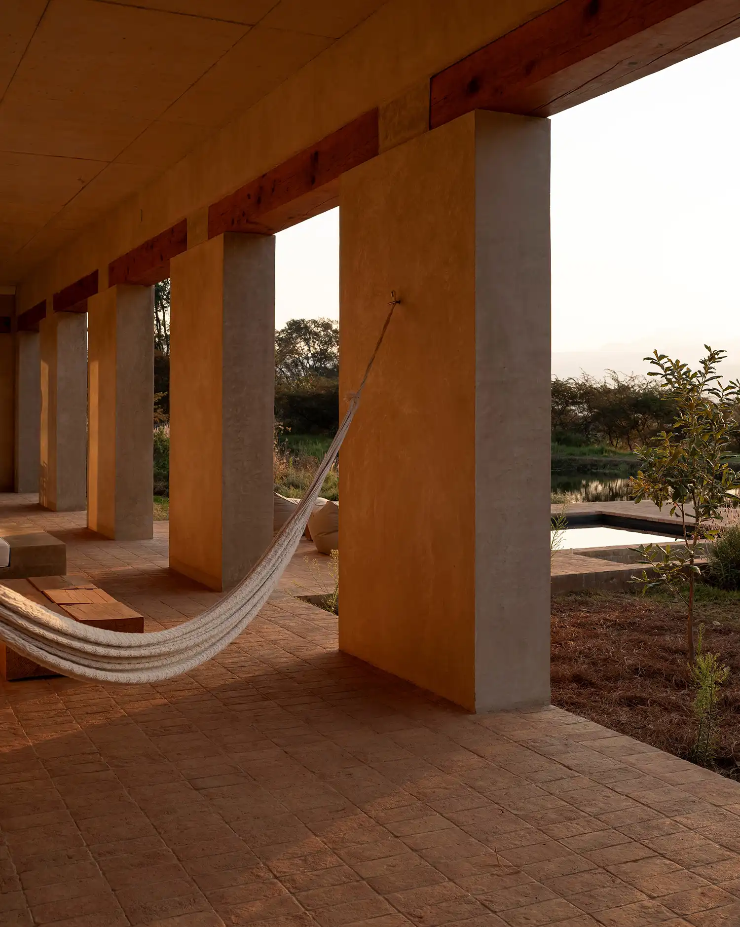 Minimalist hammock hanging in a shaded adobe corridor at Toronjos house by PPAA