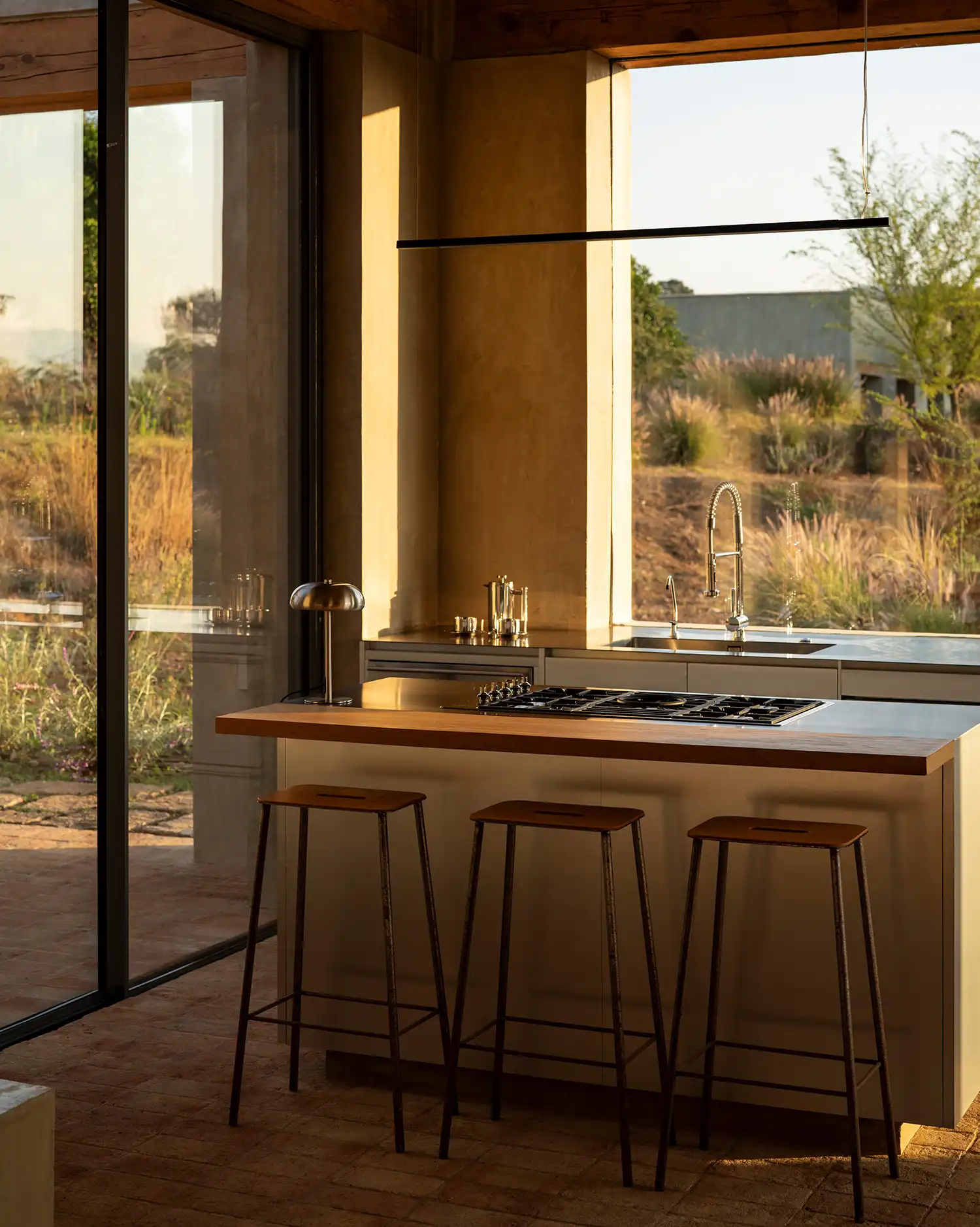 Modern kitchen interior at Toronjos with wooden island and view of the Mexican orchard