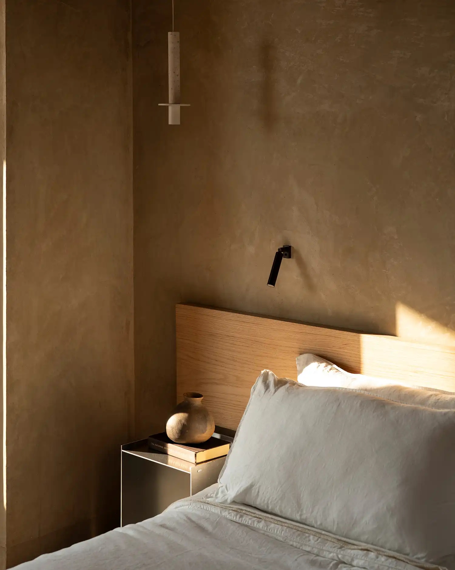 Intimate bedroom interior at Toronjos with adobe walls and warm sunlight