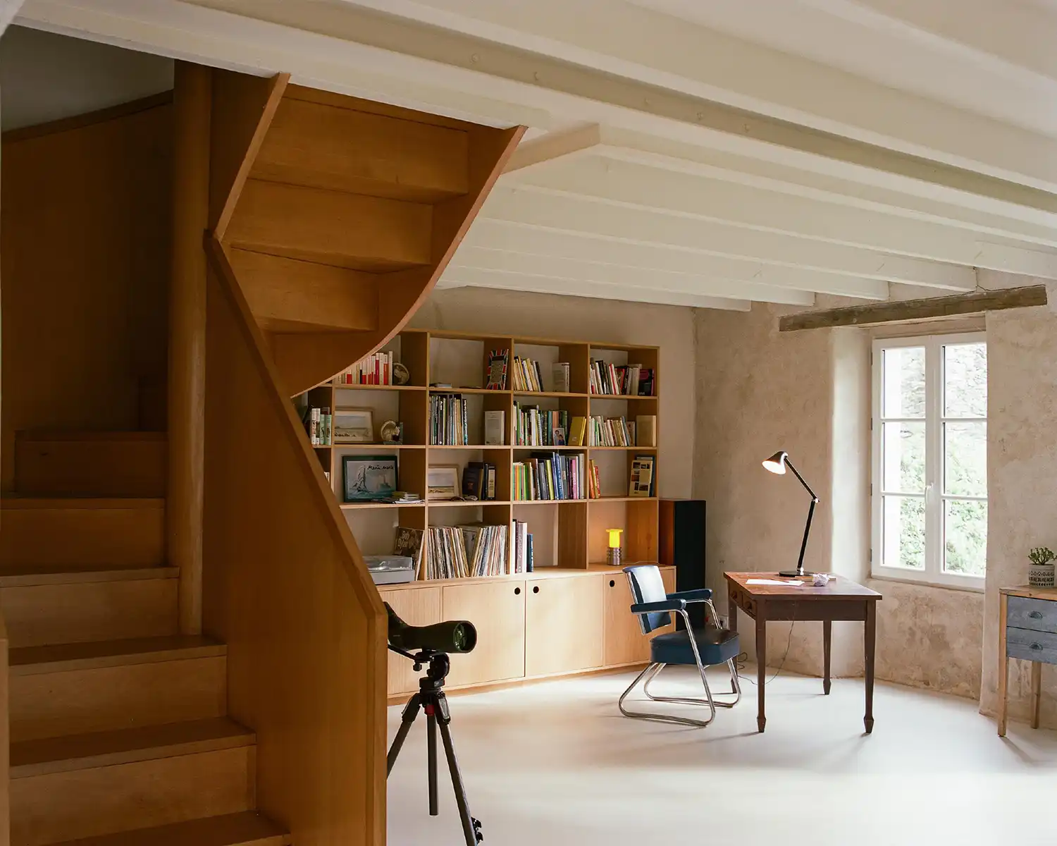 Home office and library in a French house with custom plywood shelving and a vintage desk.