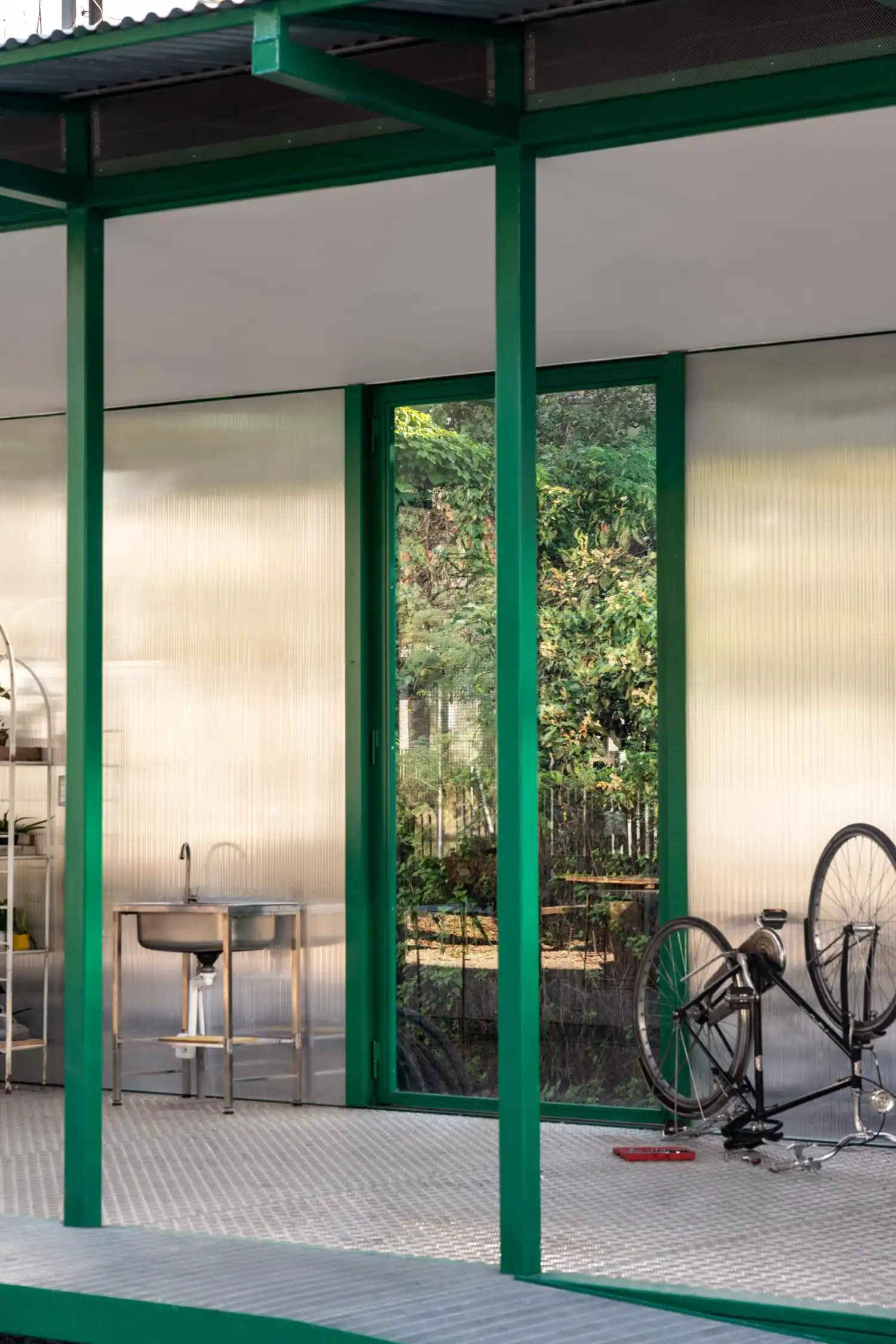 Detail of the pavilion's green steel columns and an interior stainless steel sink against translucent walls.