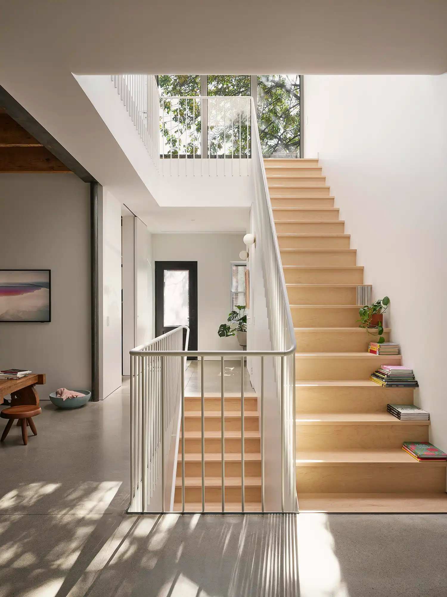 A bright, double-height interior space in a Montreal home featuring a wooden staircase and a large skylight illuminating the core.