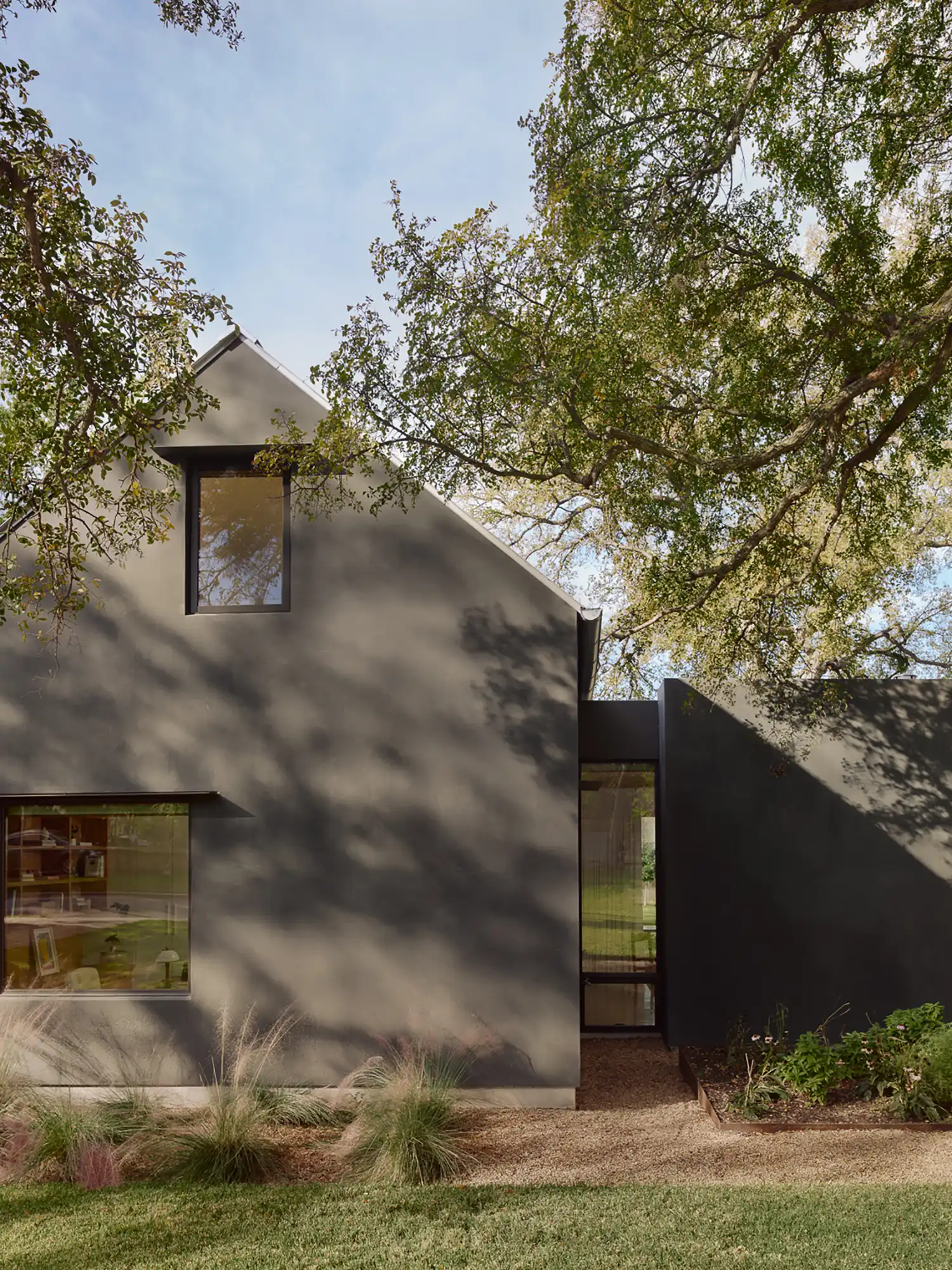 Modern dark gray exterior of the Potter residence addition with a gabled roofline and large glass windows.