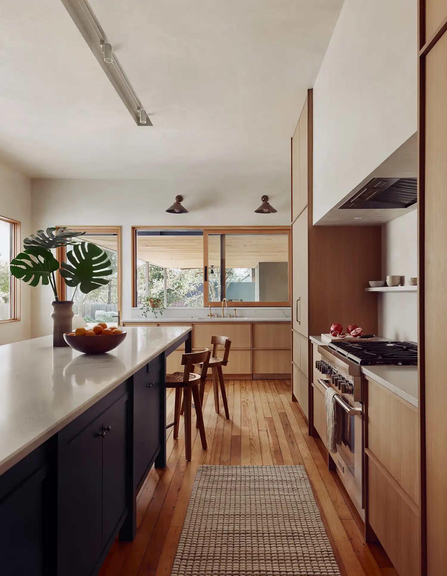 Contemporary kitchen with light wood cabinetry, white quartzite counters, and historic pine flooring.