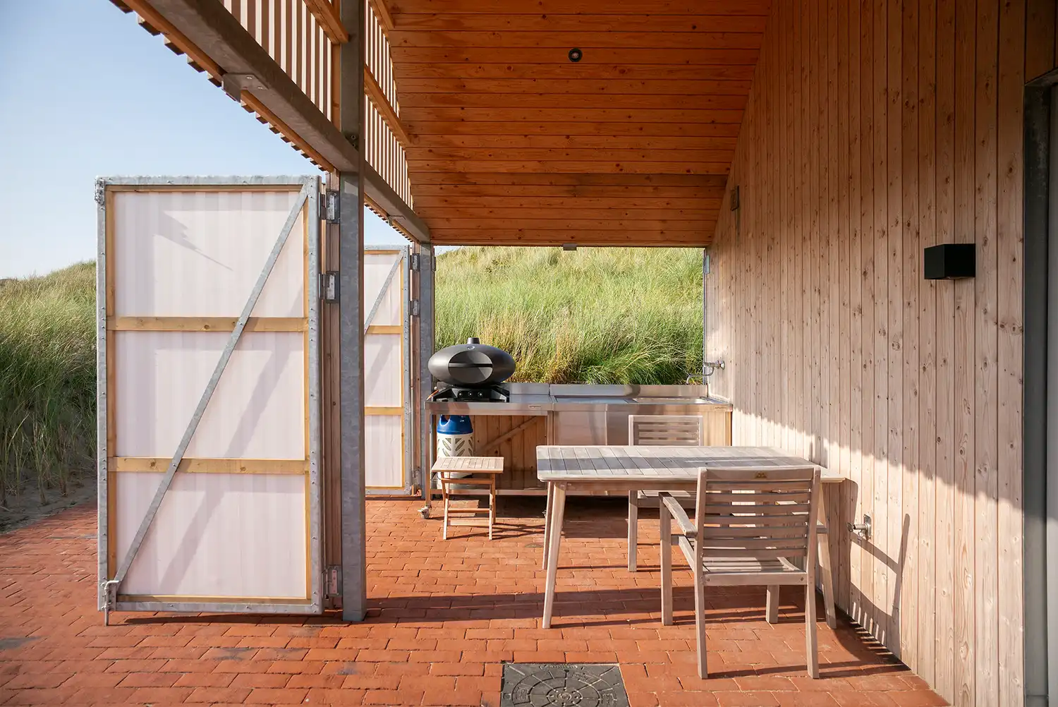 A sheltered outdoor kitchen area in a Danish retreat featuring translucent sailcloth wind screens.
