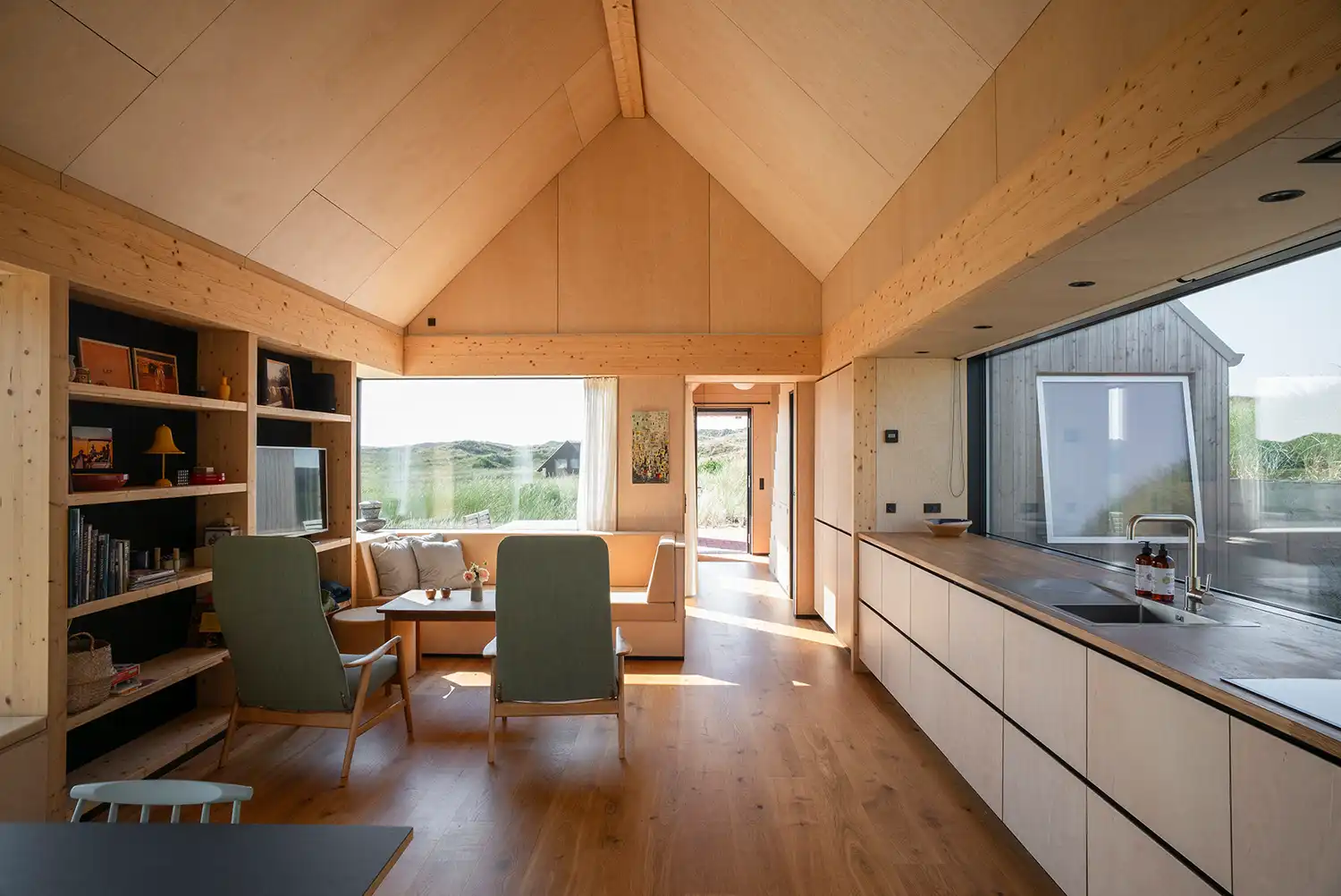 View from a minimalist kitchen toward a large window framing the Danish dunes in Klegod.