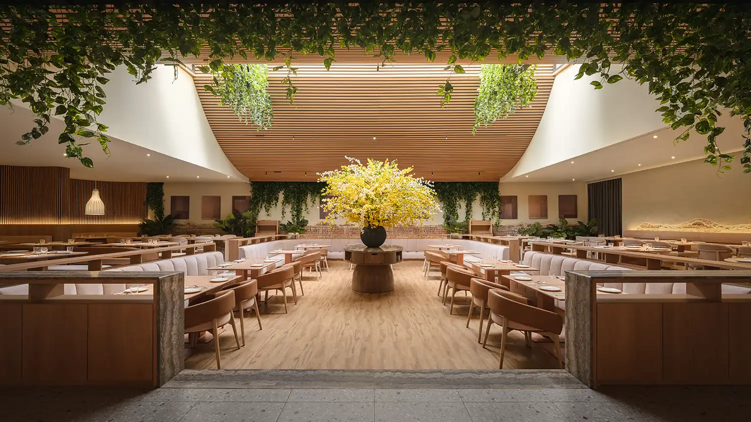 Sunken pit dining area under a linear skylight with lush hanging greenery at Sun & Moon.