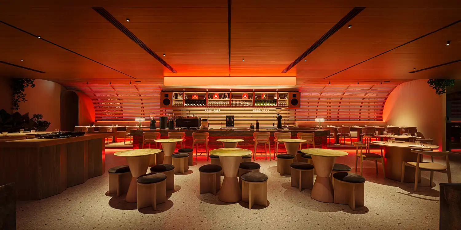 Evening view of Sun & Moon lounge with vibrant red ambient lighting and circular bar stools.