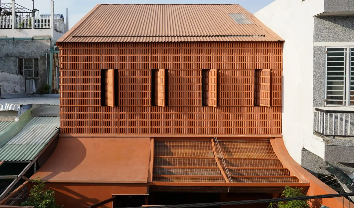Exterior view of Terracotta Breath house in Da Nang featuring a perforated brick facade and clay-colored corrugated roof.