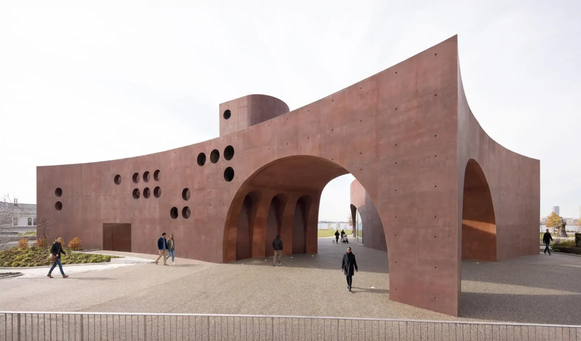 Exterior view of the Wagner Pavilion featuring deep red concrete walls and a large central arched vault.