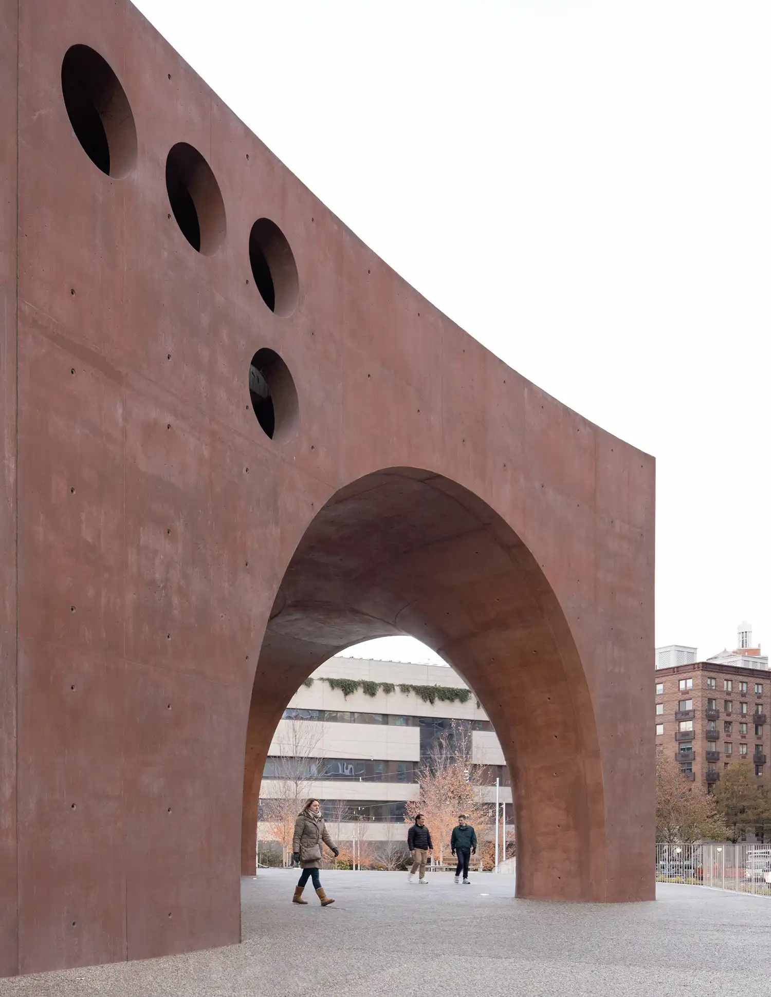 A vertical shot of a tall arched entryway with people walking through the plaza area.
