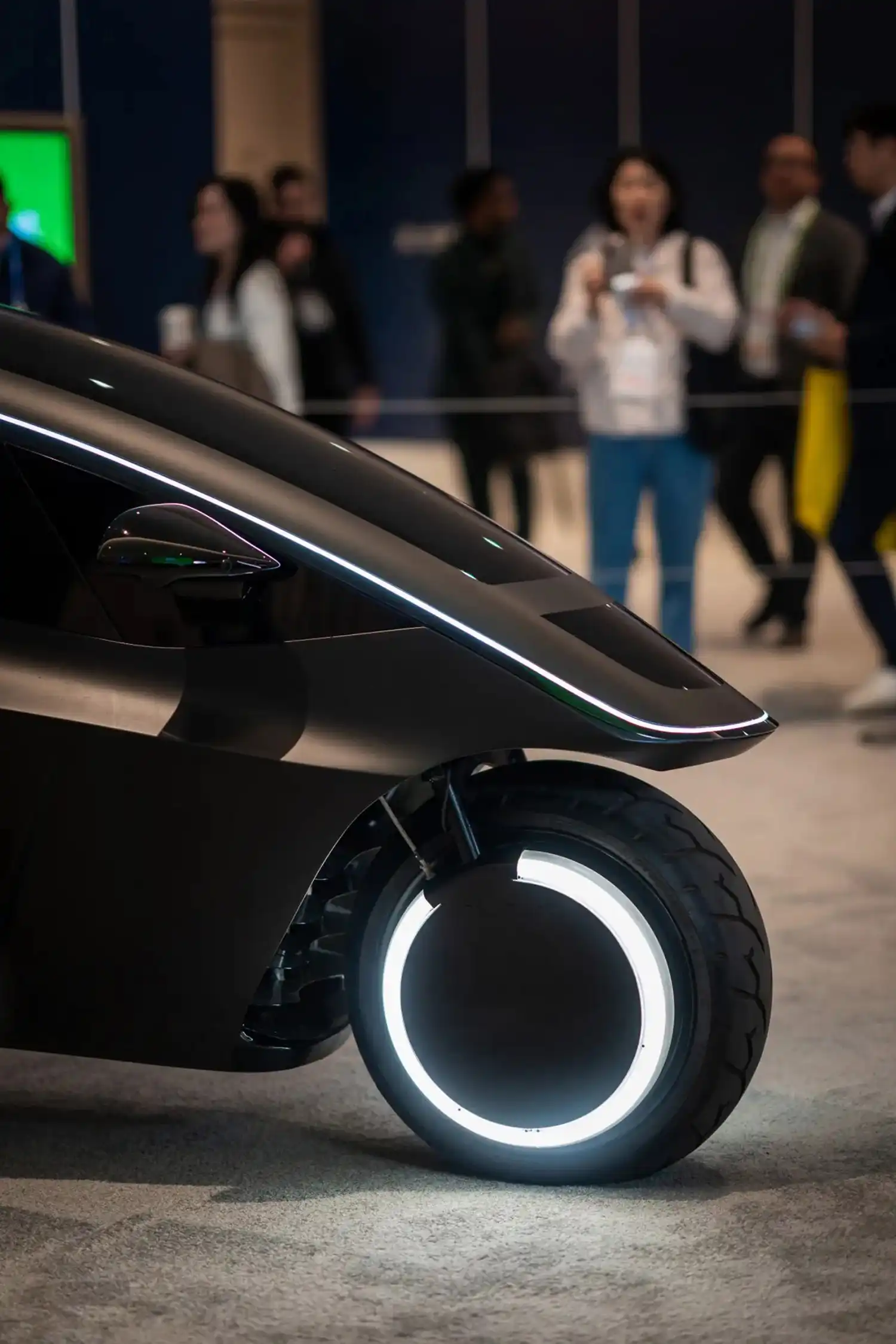 Close-up of the front wheel of the Trinity EV, featuring a glowing white LED ring and integrated fender.