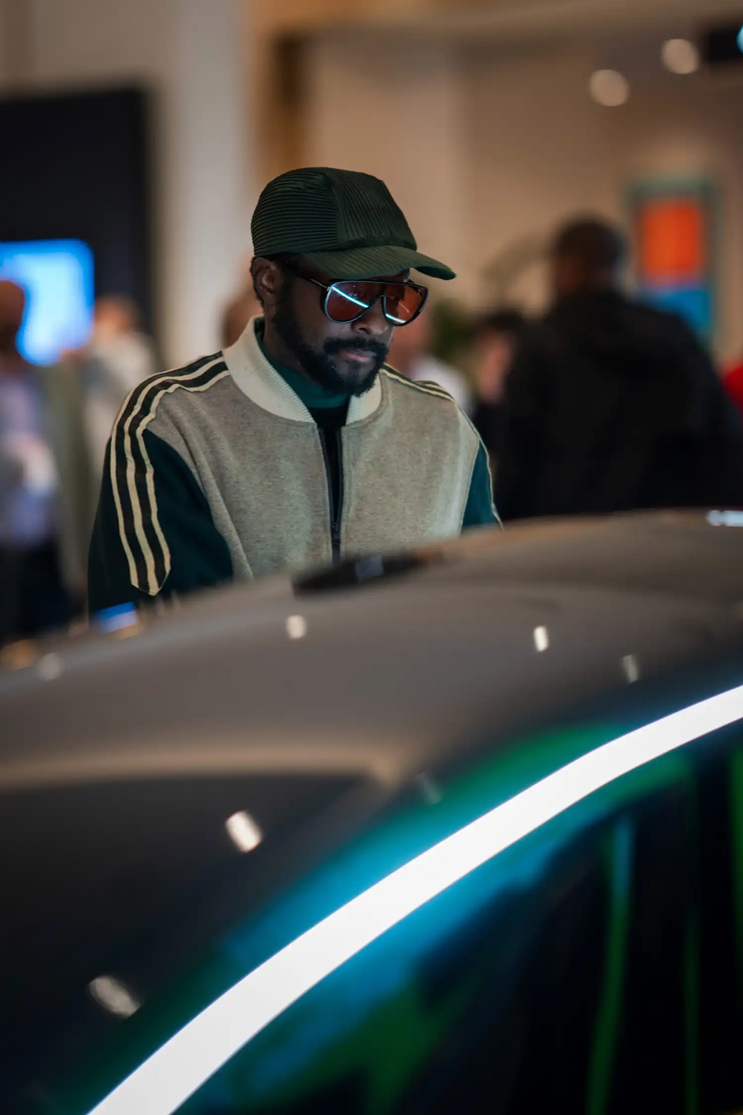 Close-up of Will.i.am looking down at the Trinity vehicle's sleek, illuminated surface.