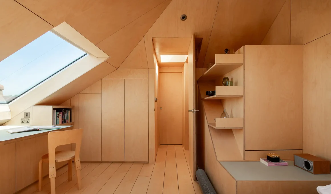 View of the birch plywood attic entrance with integrated shelving and a door leading to a hallway.
