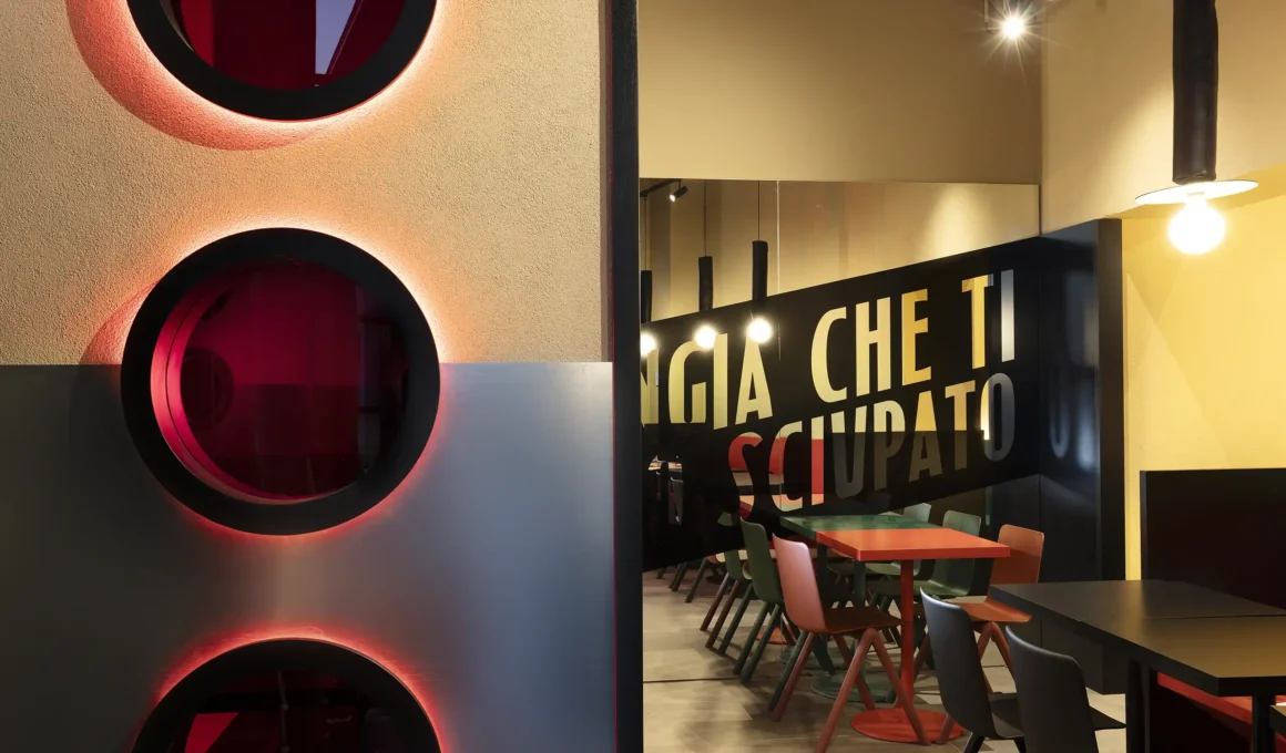 Perspective view of WÉMA interior showing red glowing portholes and a black mirrored partition with typography.