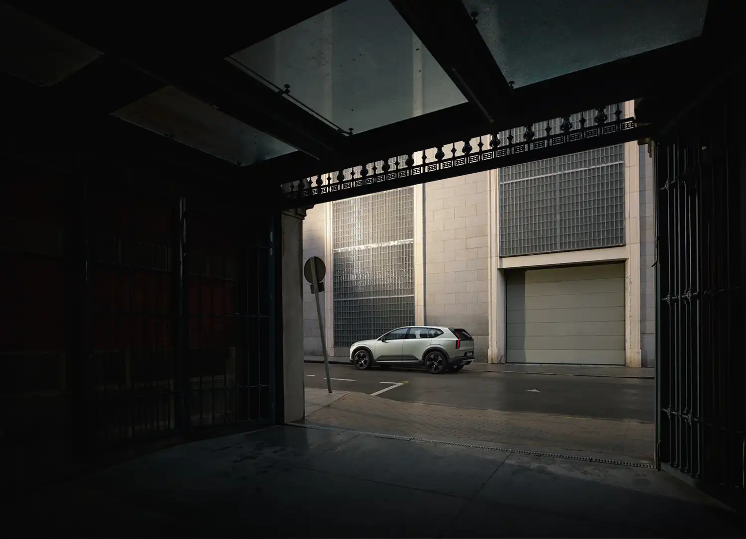 A silver Volvo EX60 parked in a modern urban alleyway during twilight.