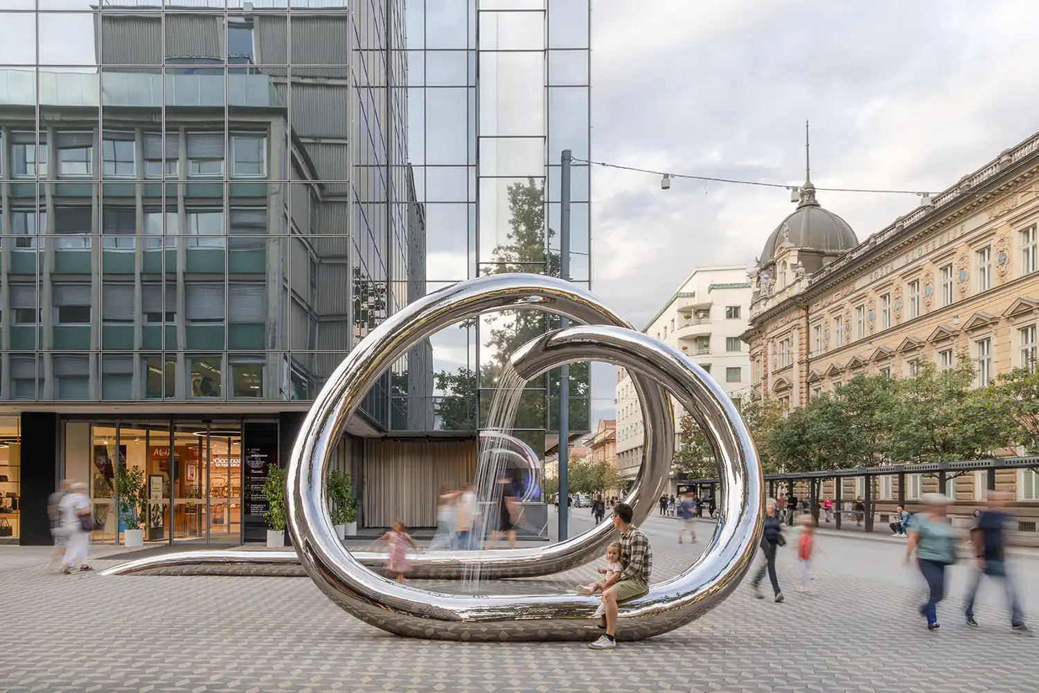 Wide shot of the interactive water sculpture with blurred movement of pedestrians.