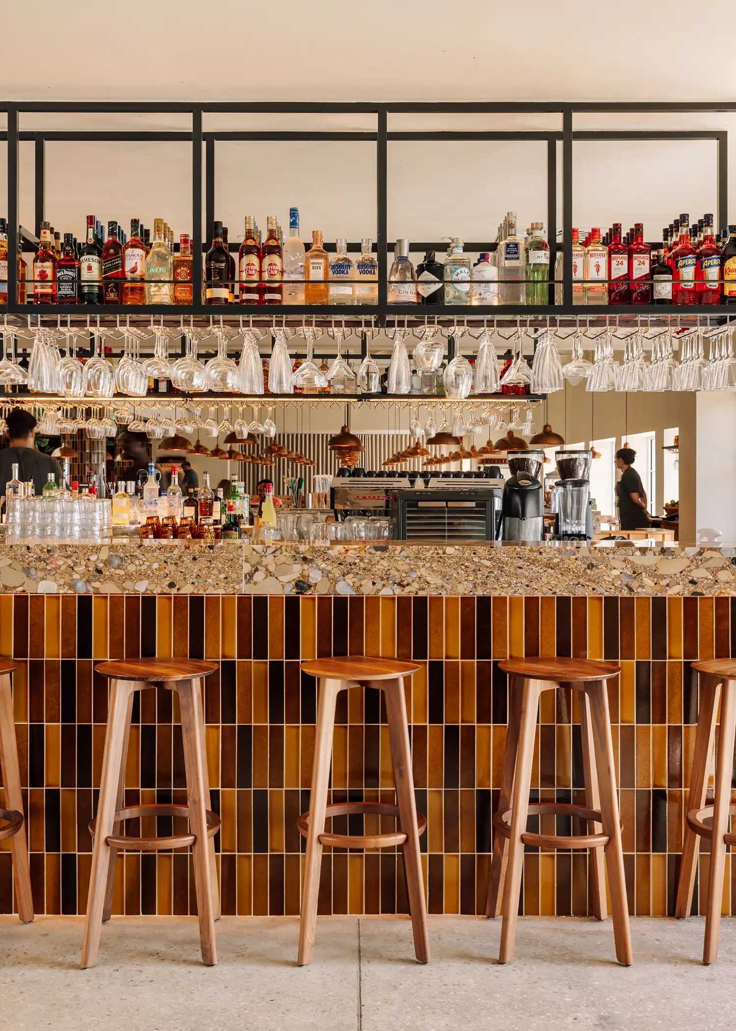 Close-up of the bar at Zero Zero Belém featuring a stone countertop and stools against amber-toned tiles.