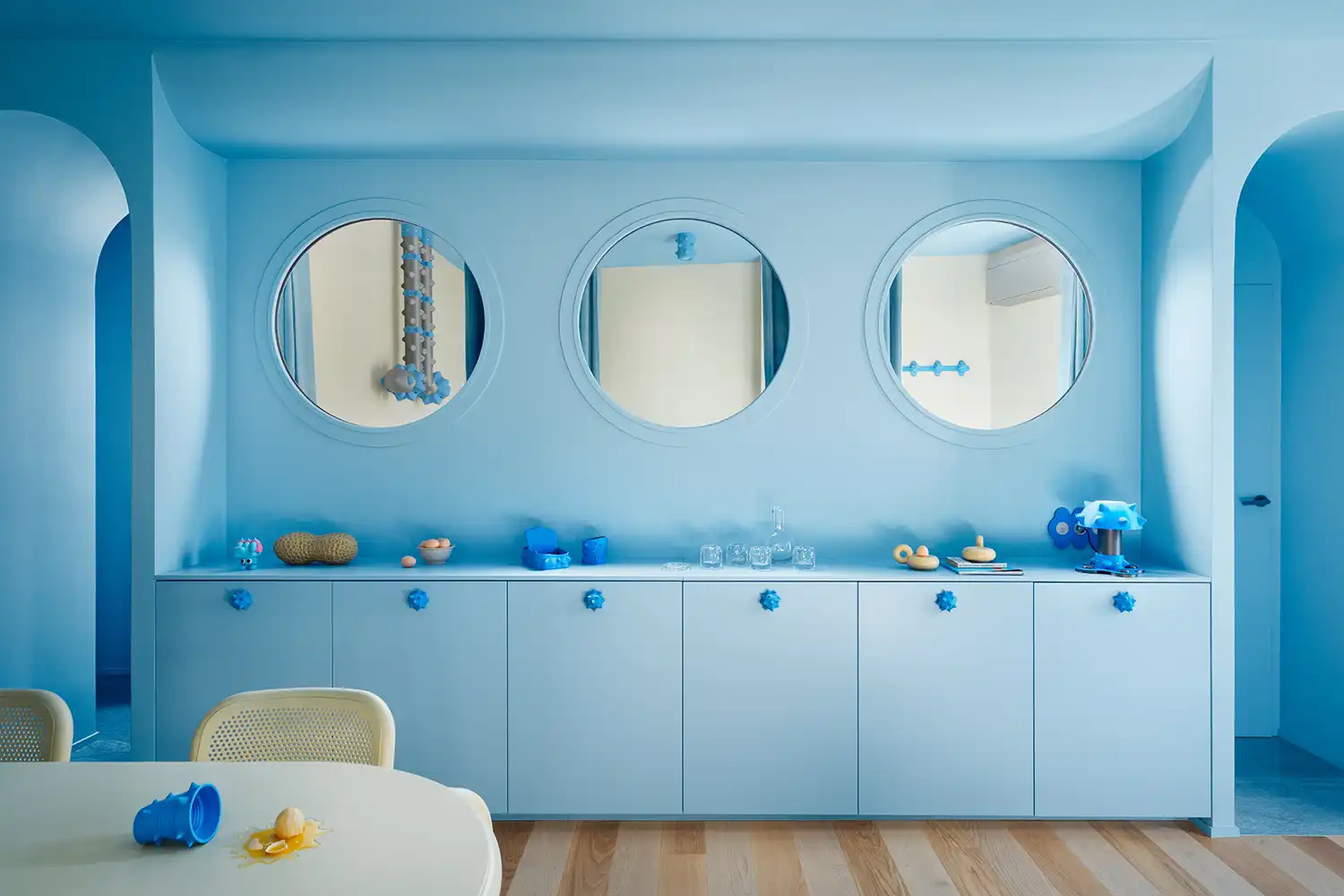 Custom storage units are punctuated by blue "urchin" handles and porthole viewports.