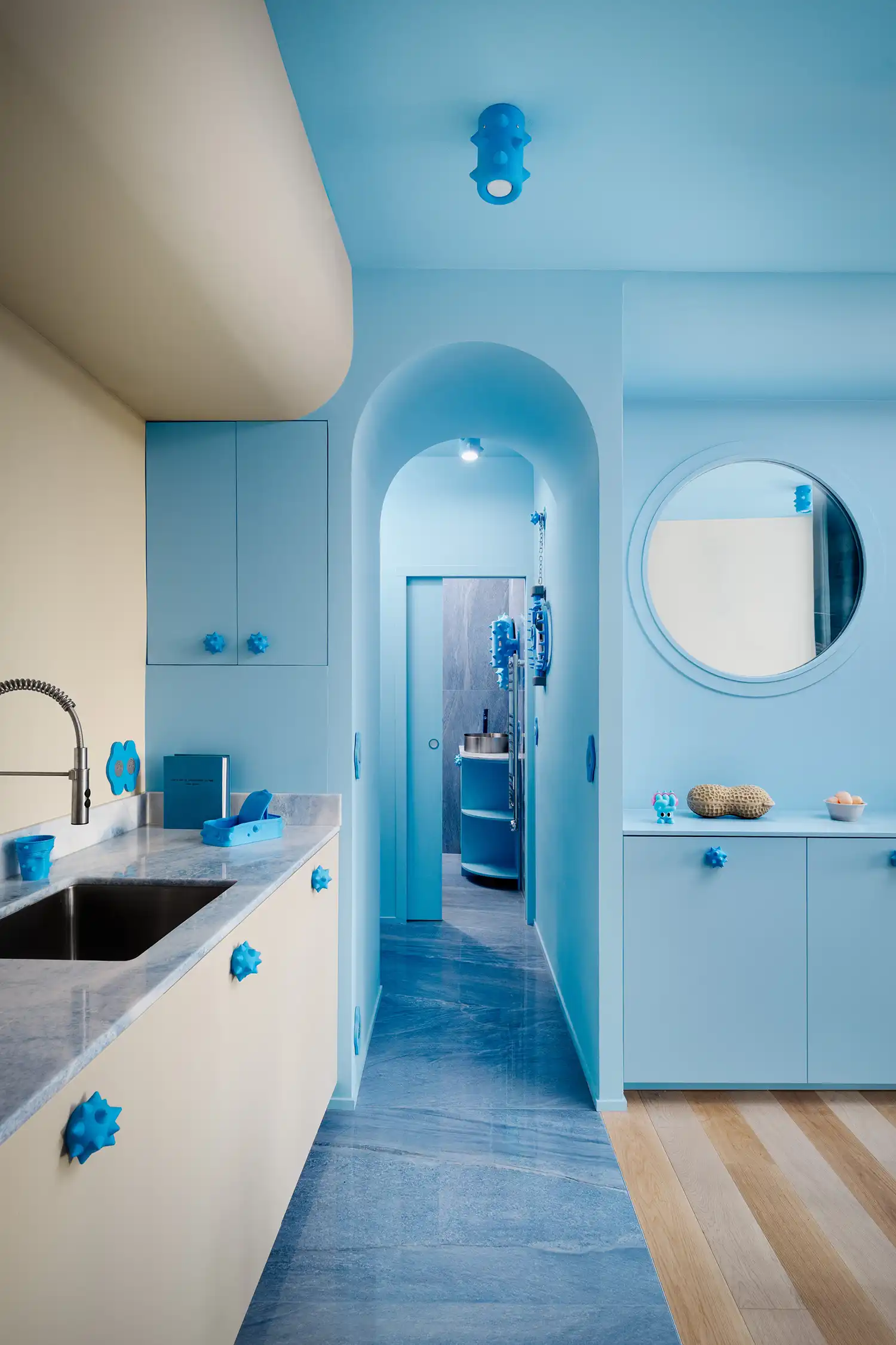 An arched doorway leads to the blue marble bathroom, evoking a dive into a mineral cave.