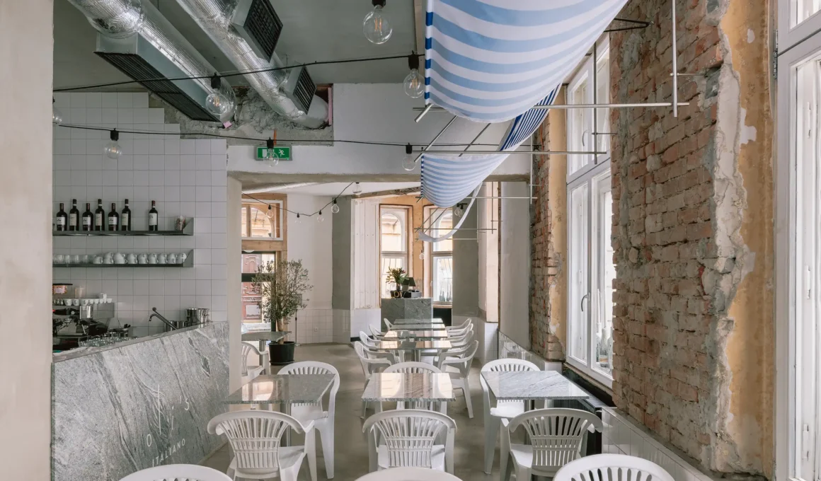 Interior of oli's ITALIANO pizzeria in Bratislava featuring raw brick walls and marble tables.