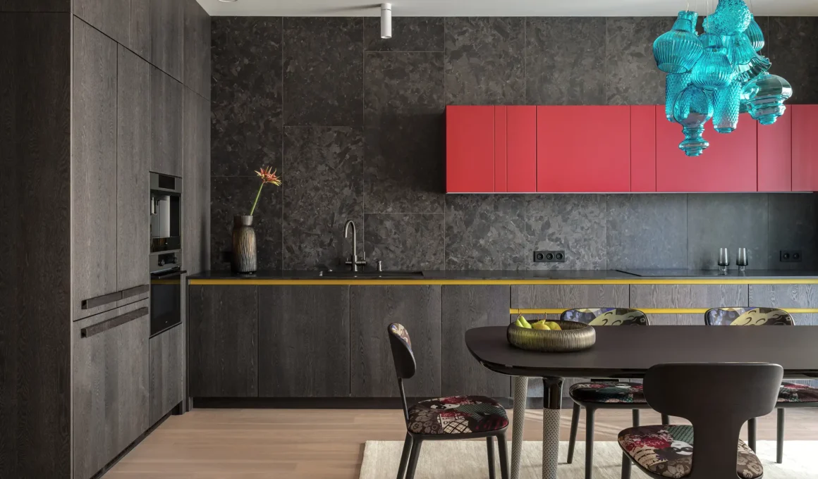 Modern dark ash kitchen with a bold raspberry-hued wall cabinet and turquoise Karman chandelier.