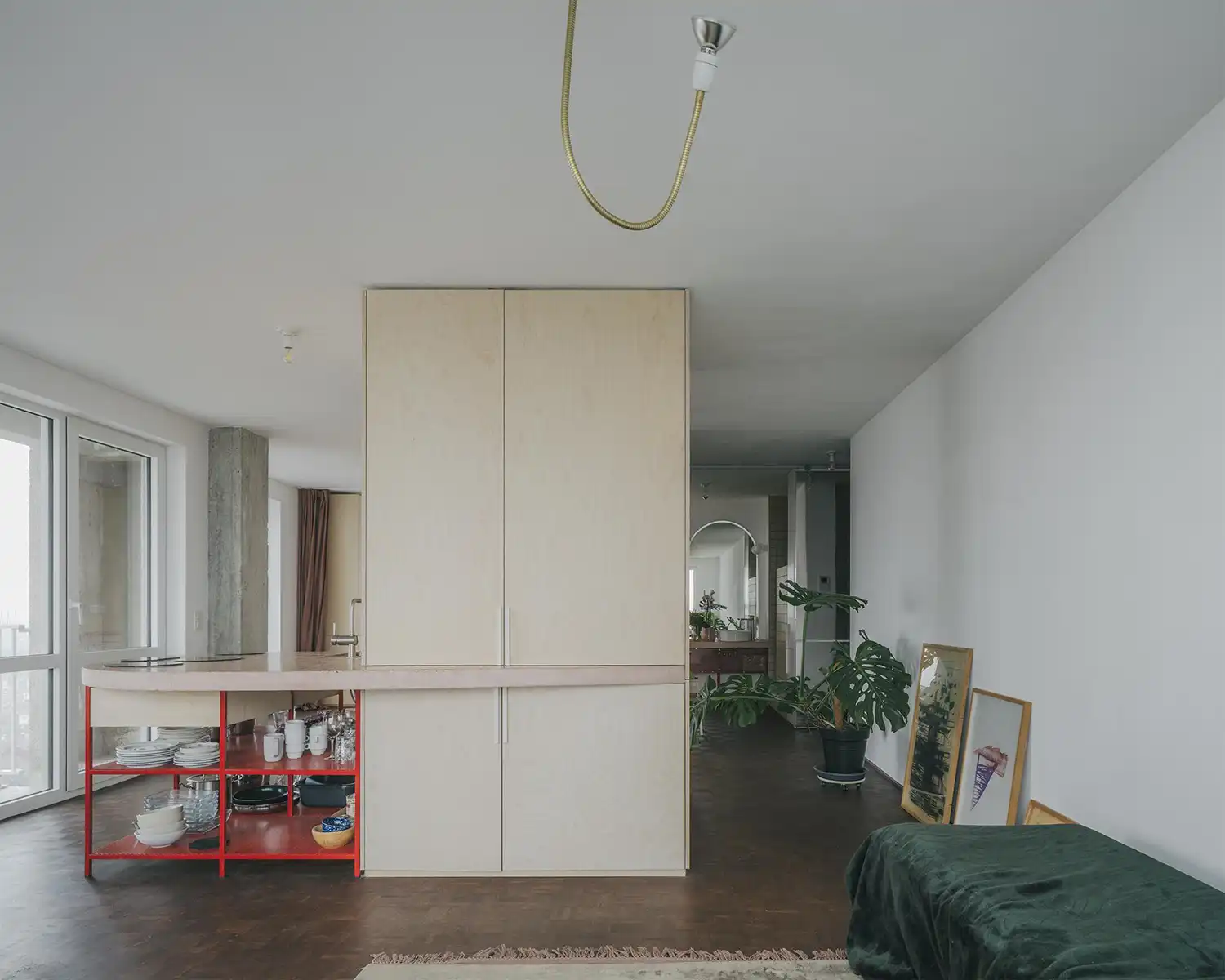 Central plywood partition wall separating the kitchen and living areas in a Brussels high-rise.