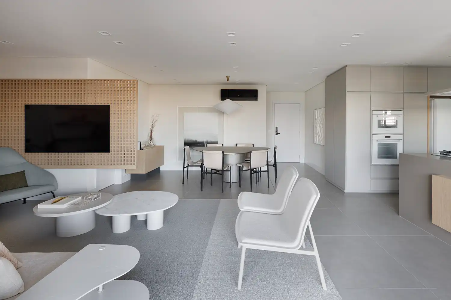 A wooden slatted partition wall with a built-in TV screen separating social zones.