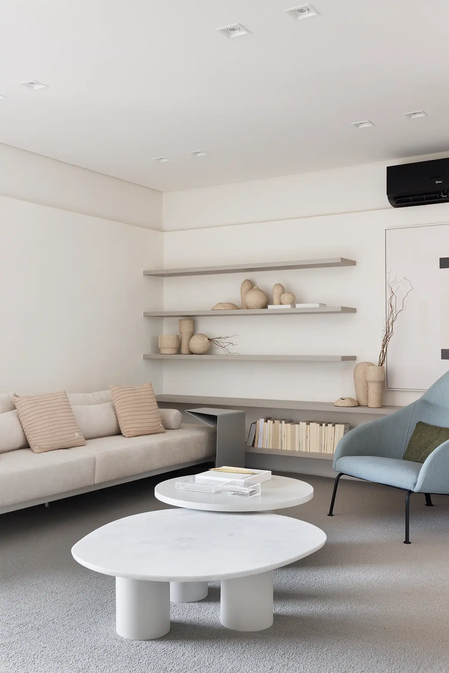 Close-up of minimalist shelving with handcrafted ceramic vessels and neutral-toned books.