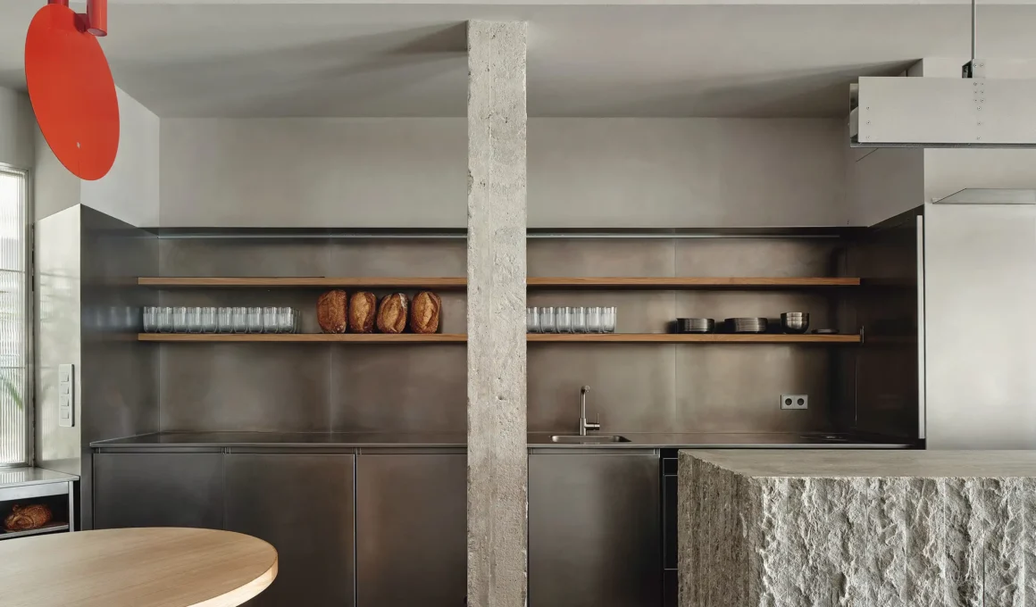 Close-up of a brutalist split-stone counter and stainless steel kitchen in Santander.