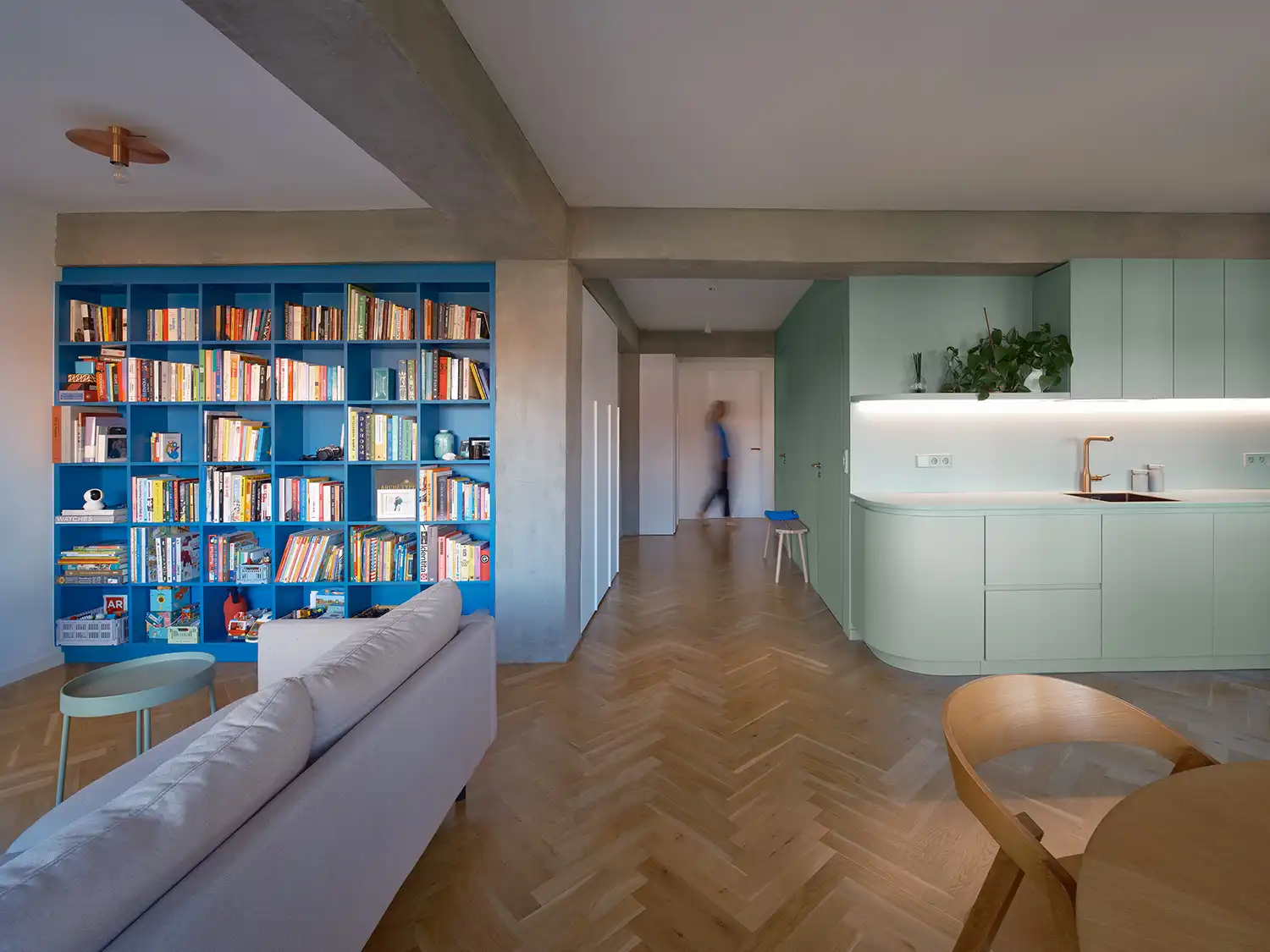 Wide view of a living room featuring a floor-to-ceiling blue bookshelf and a green central core.