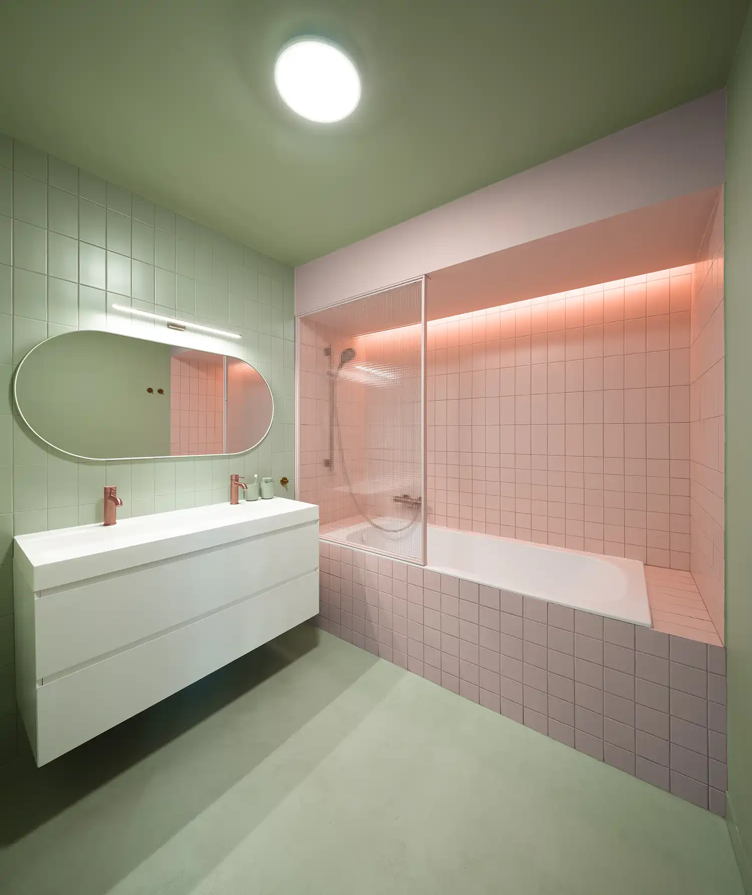 Contemporary bathroom featuring sage green tiles, a pink tiled bathtub nook, and copper fixtures.
