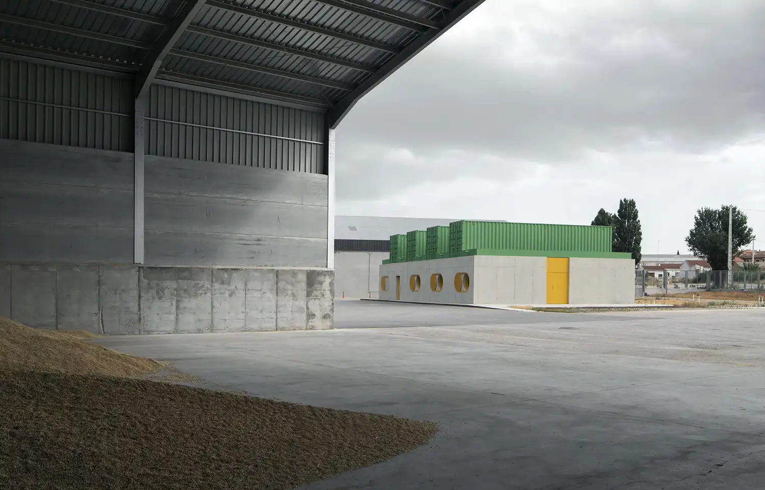 Wide shot of the Agrosemillas headquarters in a vast industrial yard with grain piles