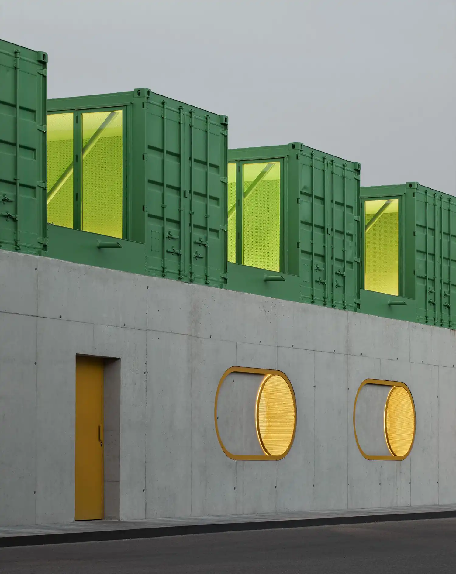 Night view of the Agrosemillas offices with glowing yellow windows and green containers