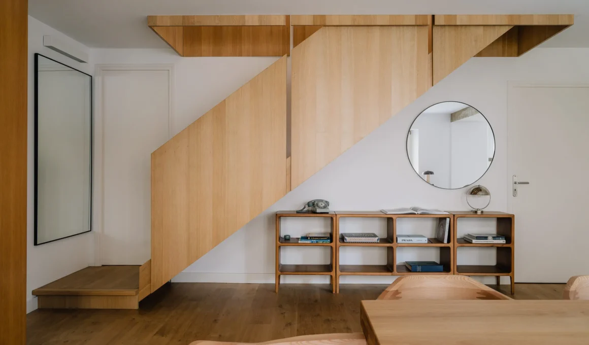 Minimalist oak staircase with geometric wood paneling and a circular mirror.