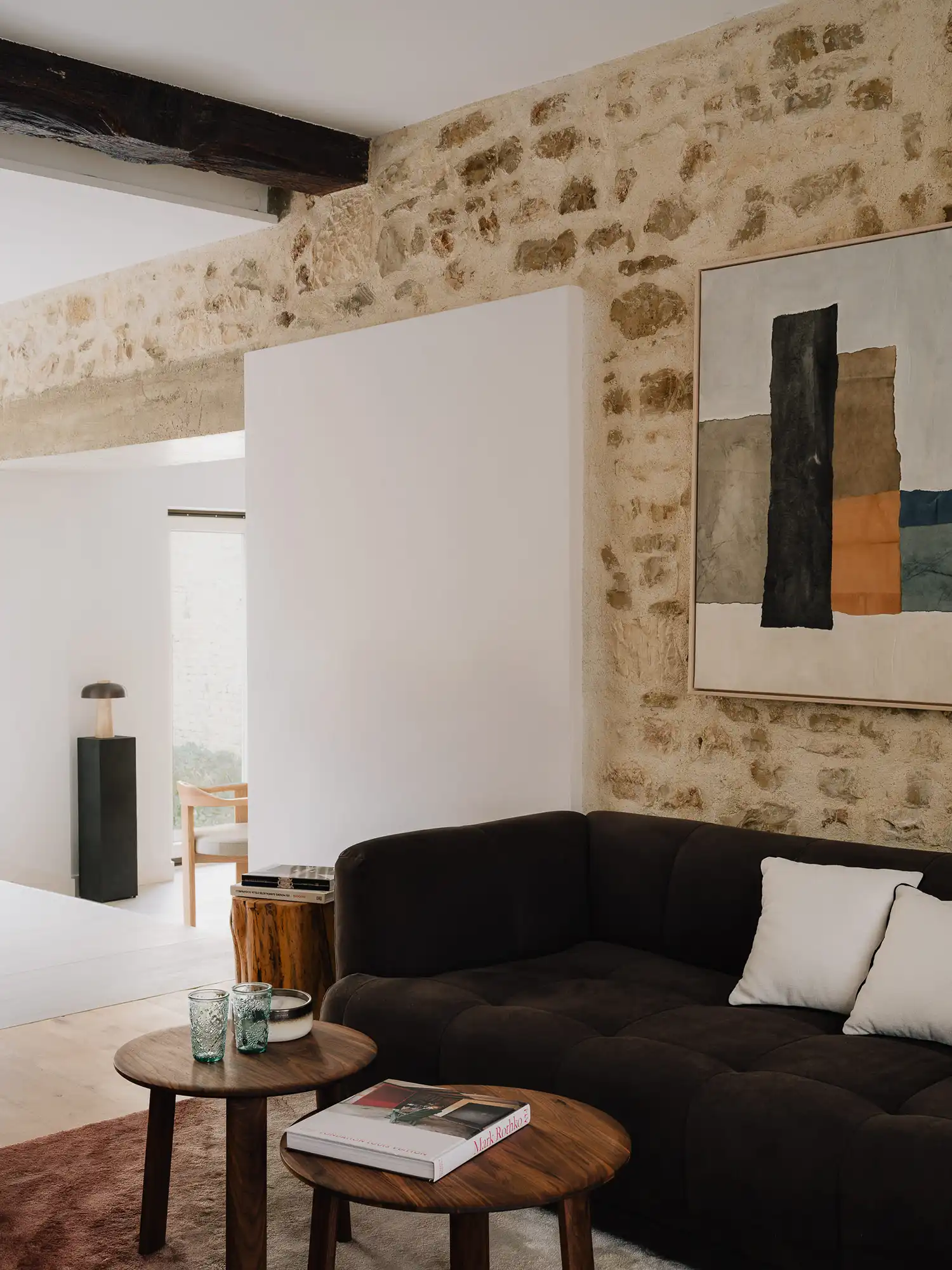 Living room with exposed stone wall, dark contemporary sofa, and abstract art.