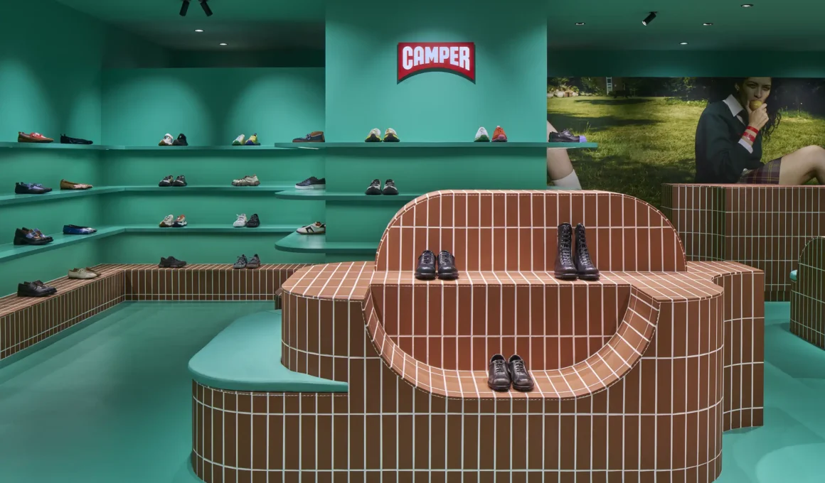 Wide view of a teal monochromatic retail space with curved terracotta tile display islands.