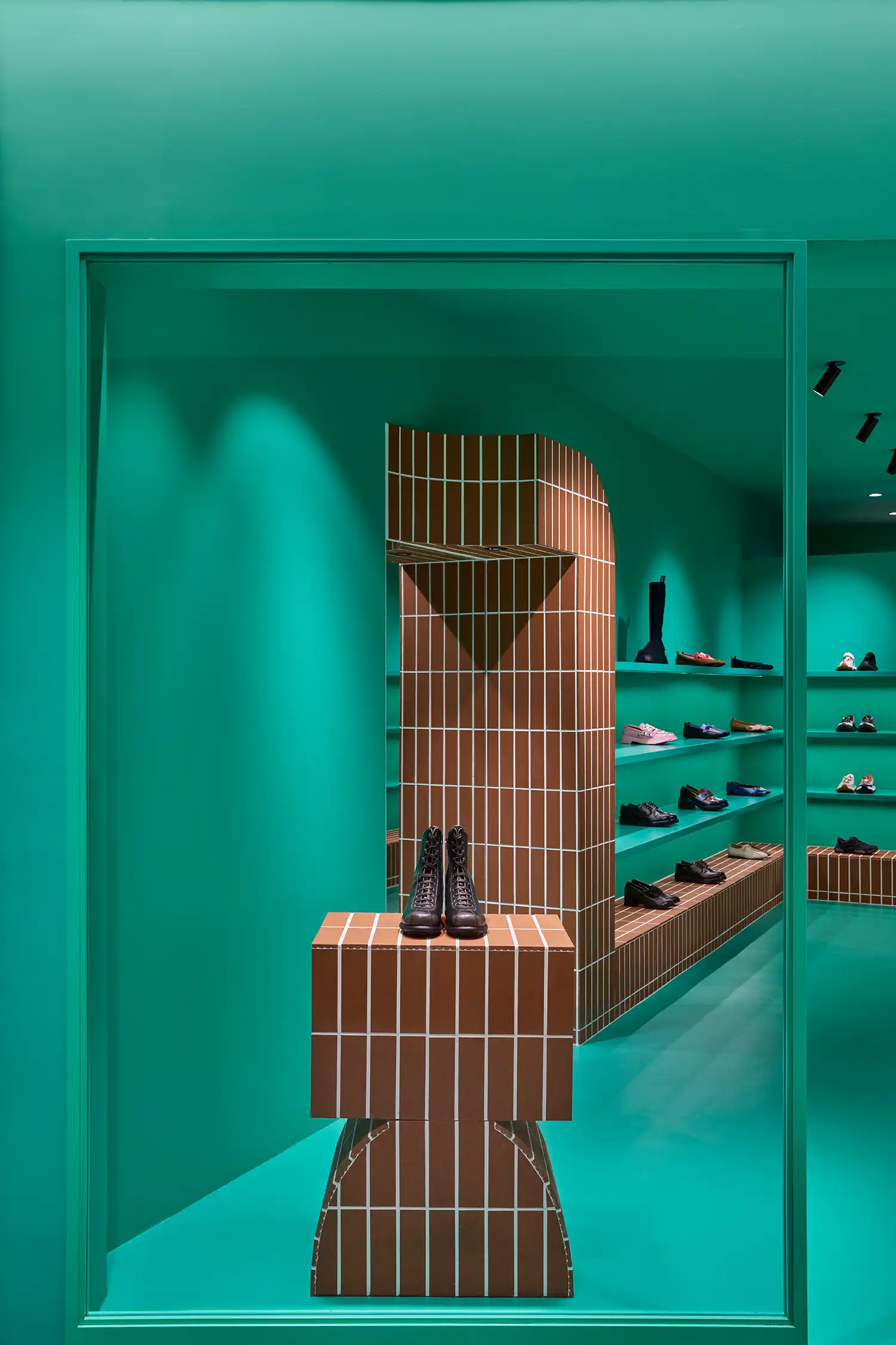 Vertical shot through a doorway of a geometric terracotta column and teal shelving.