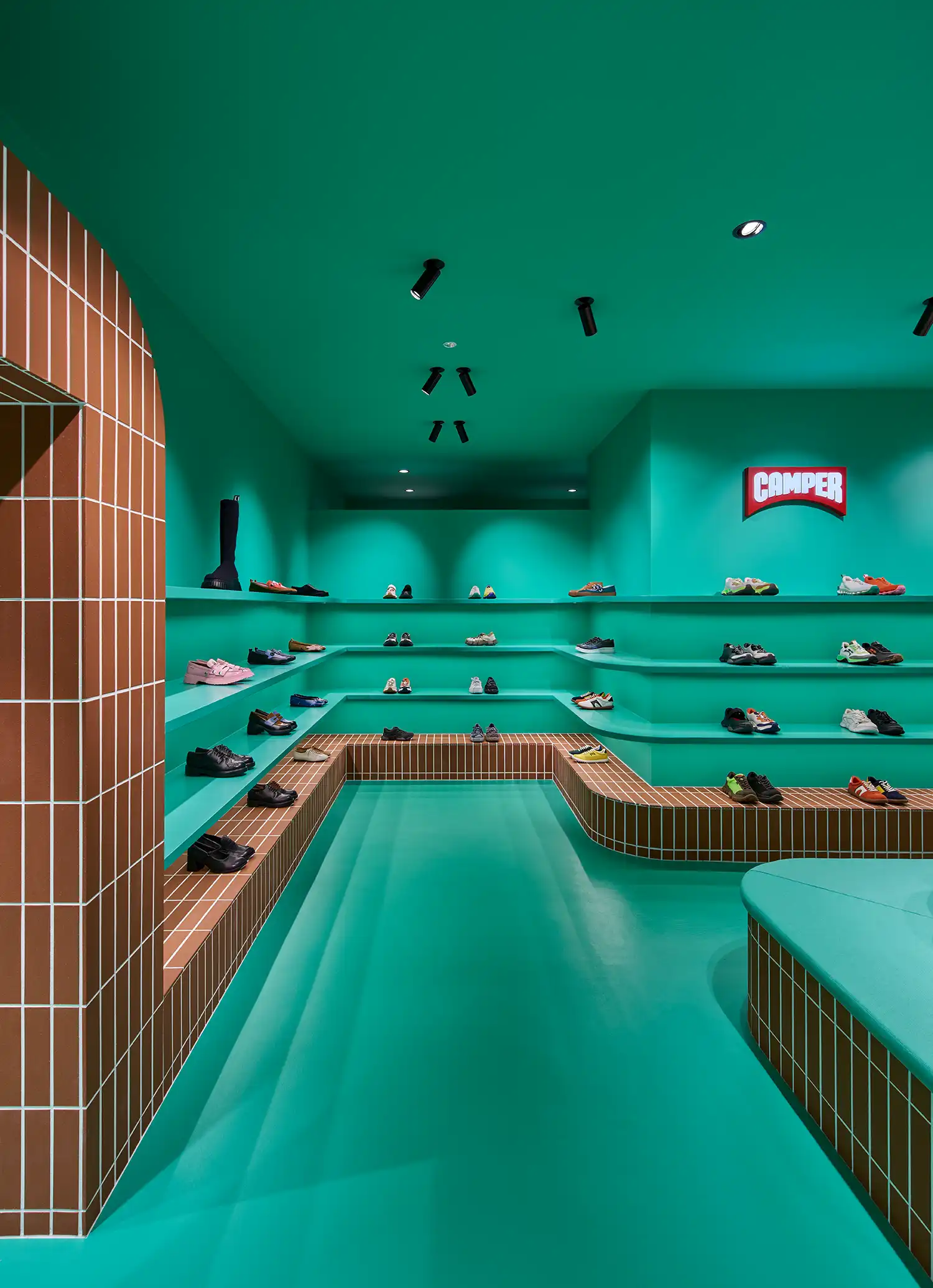 Deep perspective of teal walls and integrated shelving with a low terracotta tile perimeter.