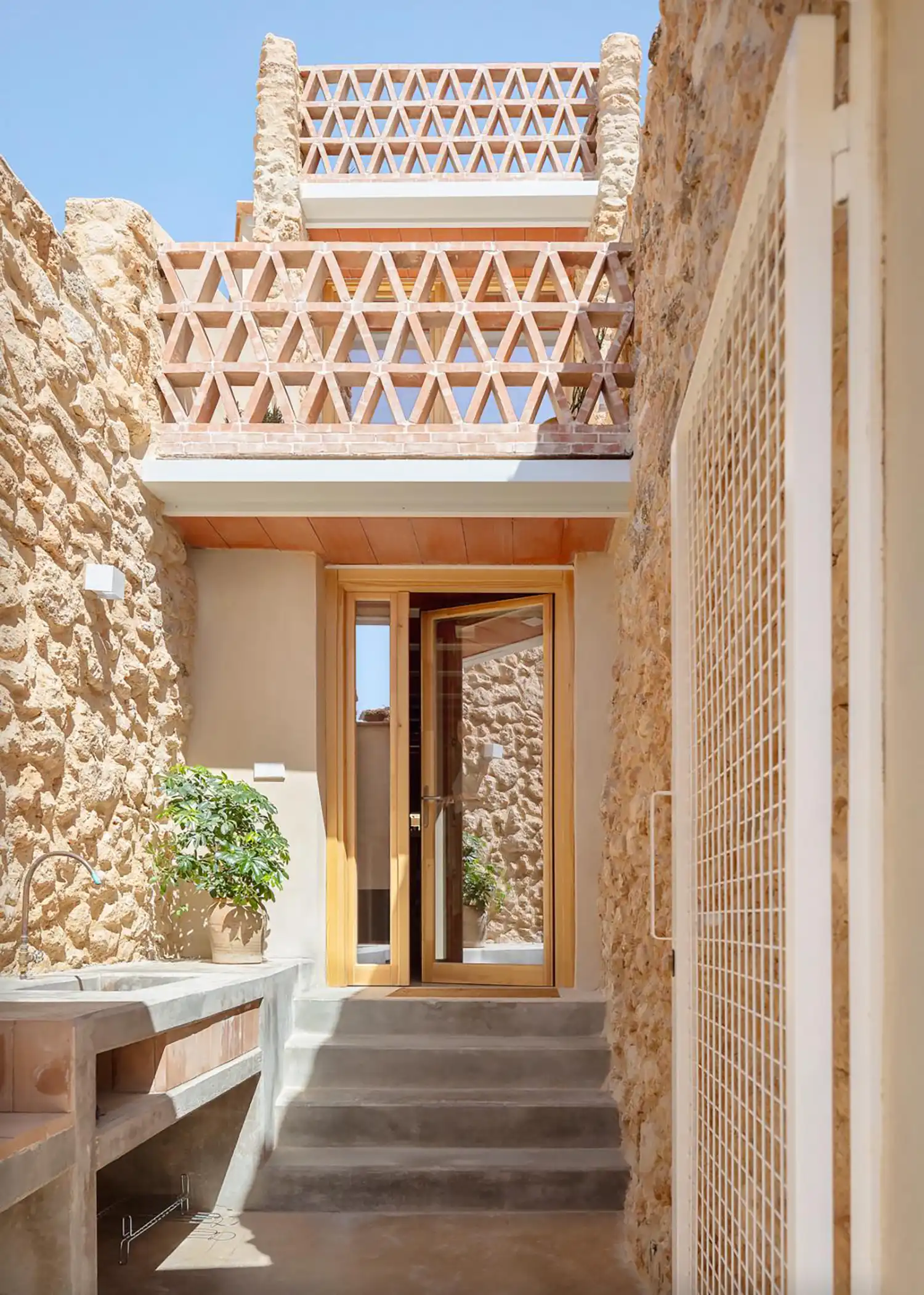 Sunlit courtyard entrance of Casa Felipa featuring stone walls and a concrete sink.