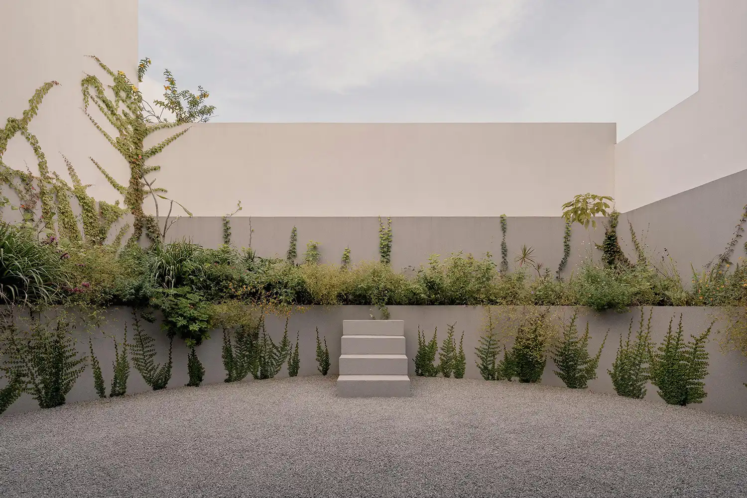 Symmetrical rear facade of Casa Tlaloc with three levels of glass and concrete.