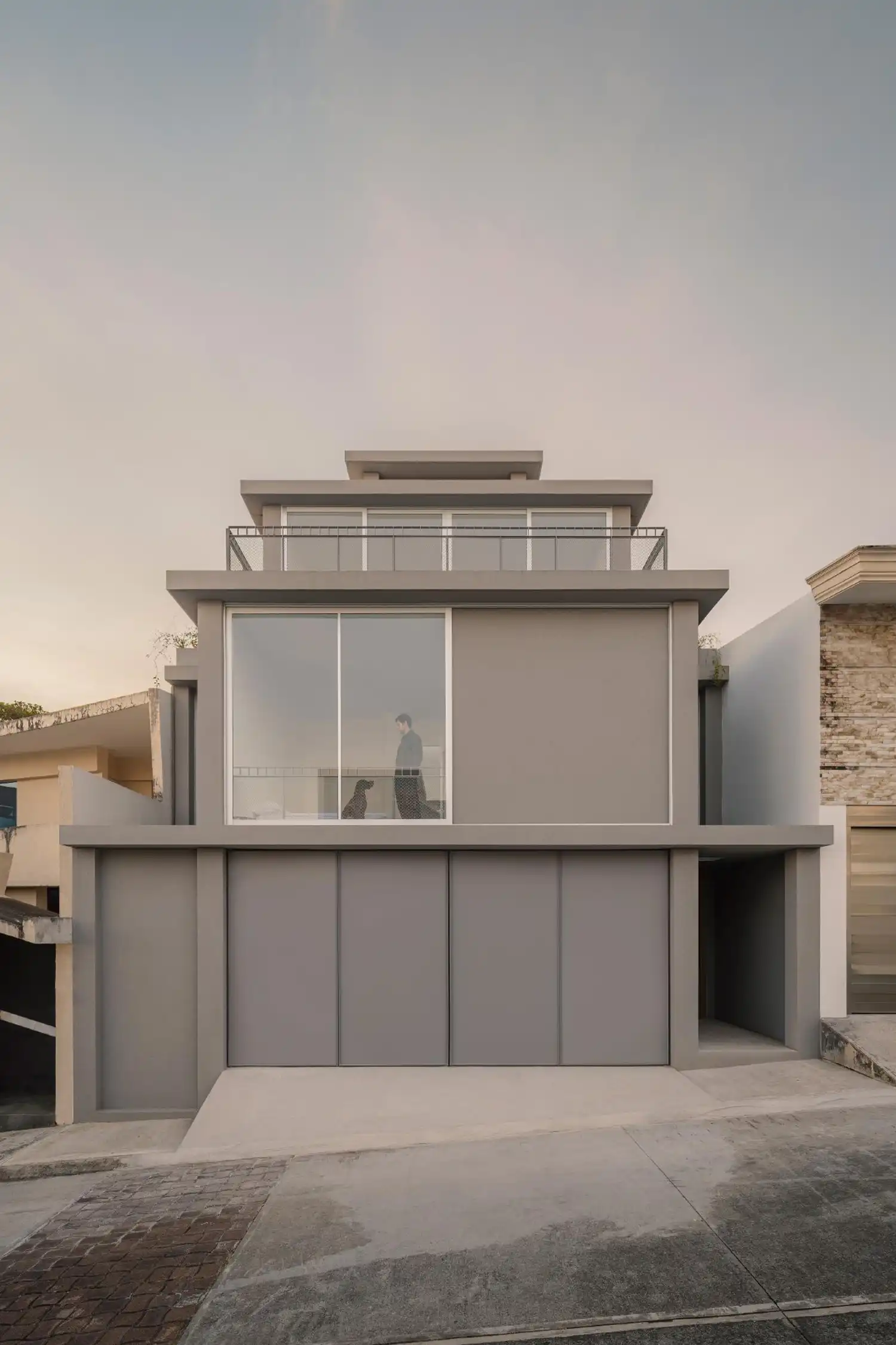 Minimalist gravel courtyard with curved concrete walls and climbing plants.