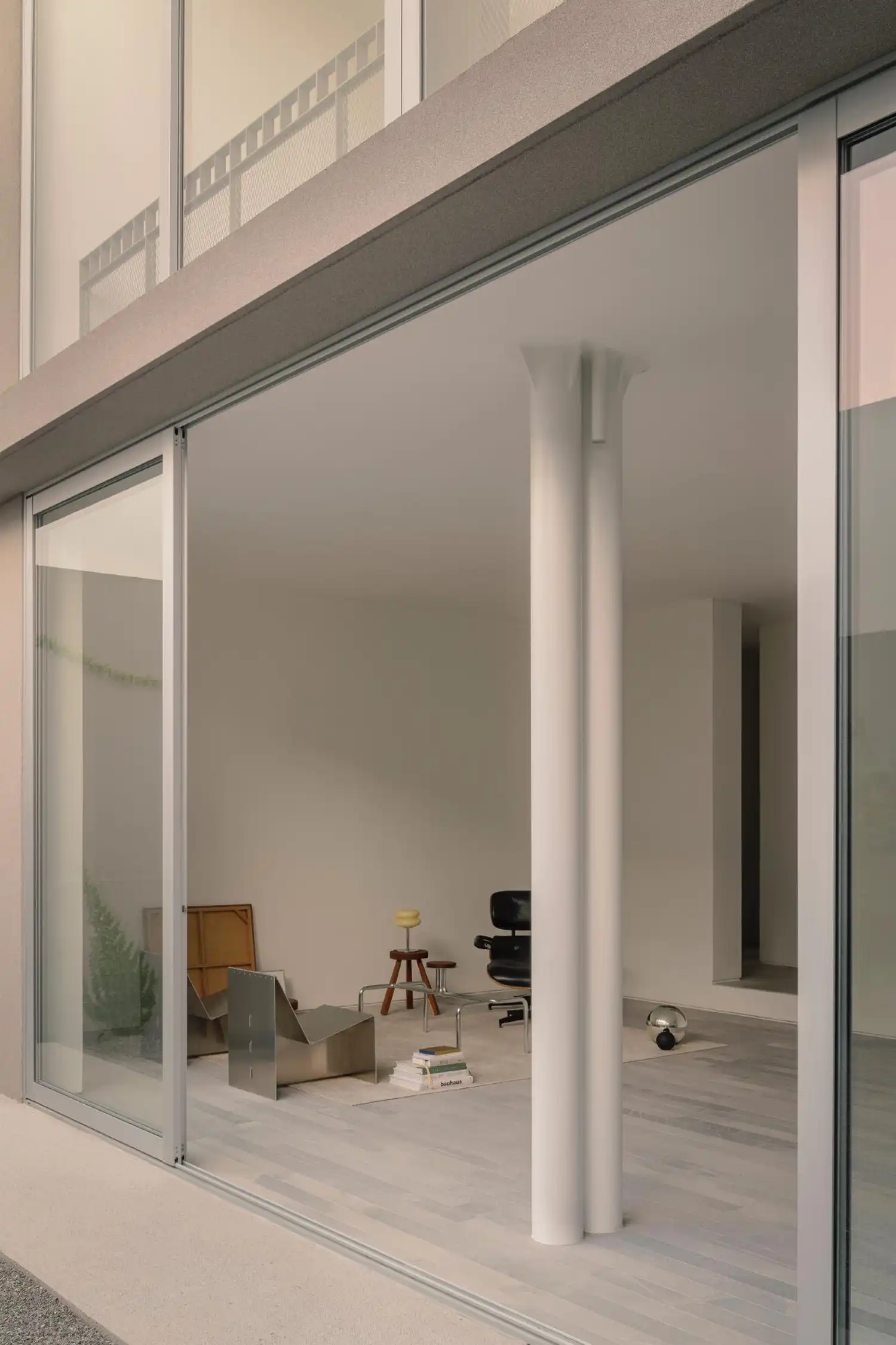 Minimalist living area with white double columns and an Eames lounge chair.