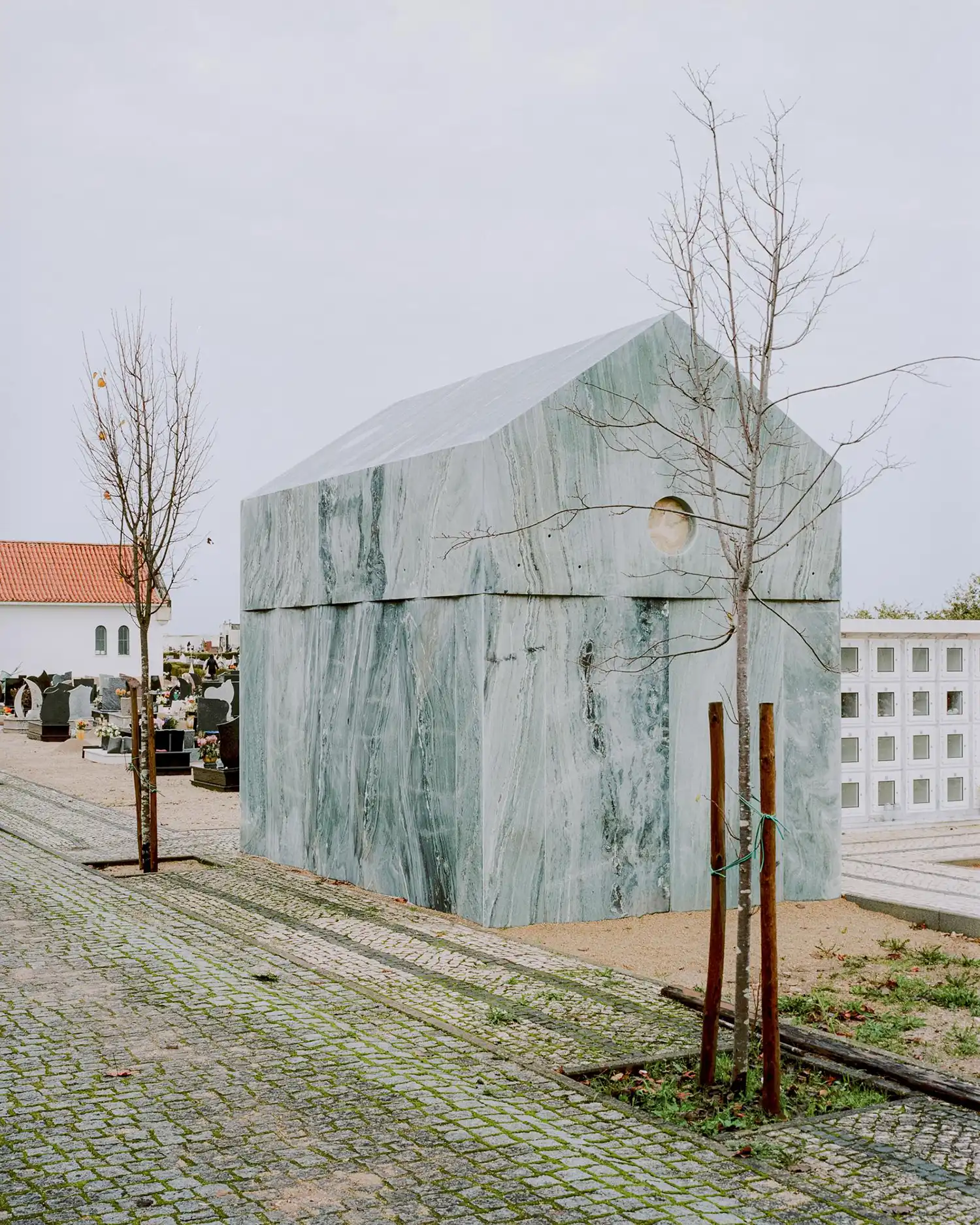 Three-quarter view of the marble tomb in Coimbra under overcast light.