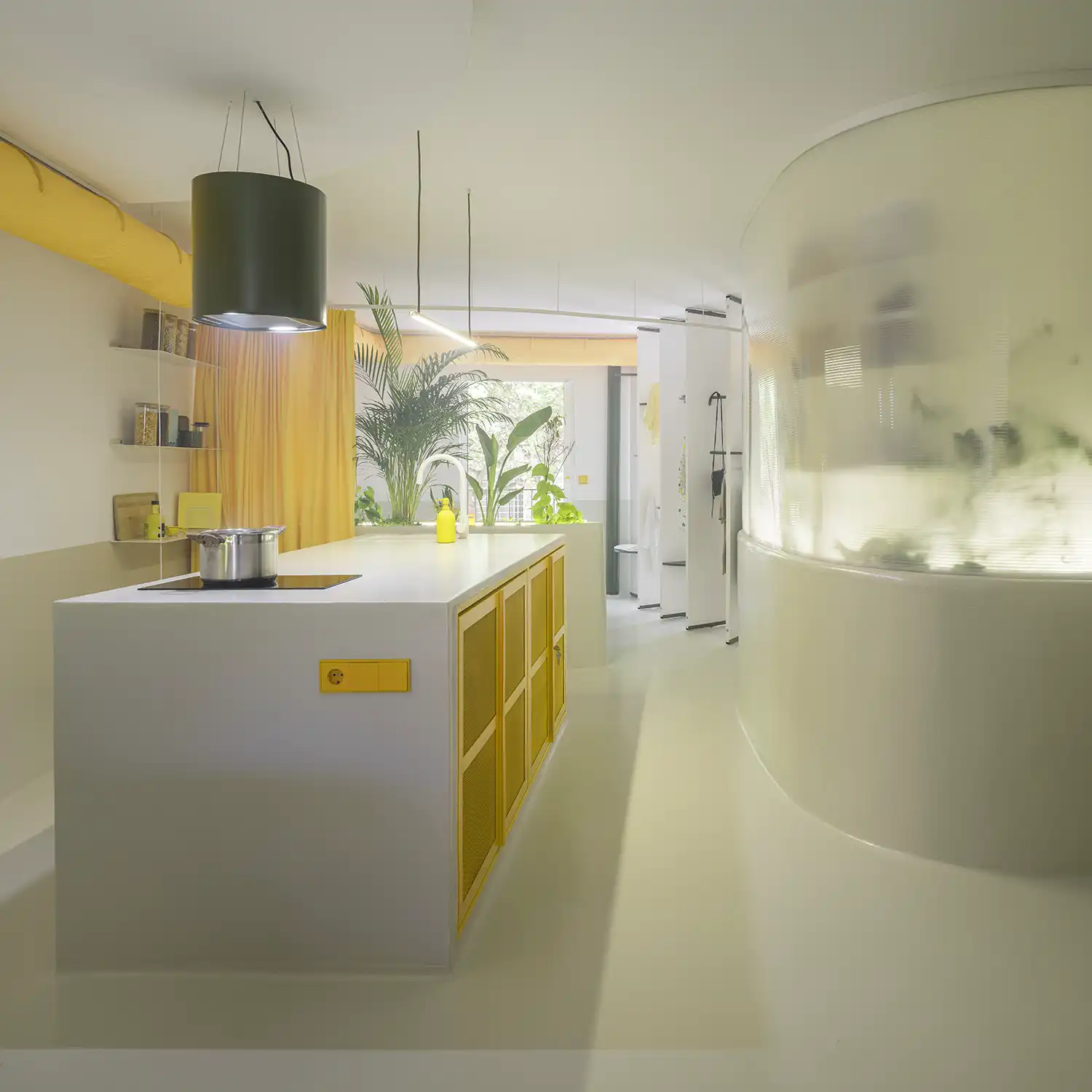 Modern white kitchen island with yellow metal mesh doors and a curved translucent wall in the background.
