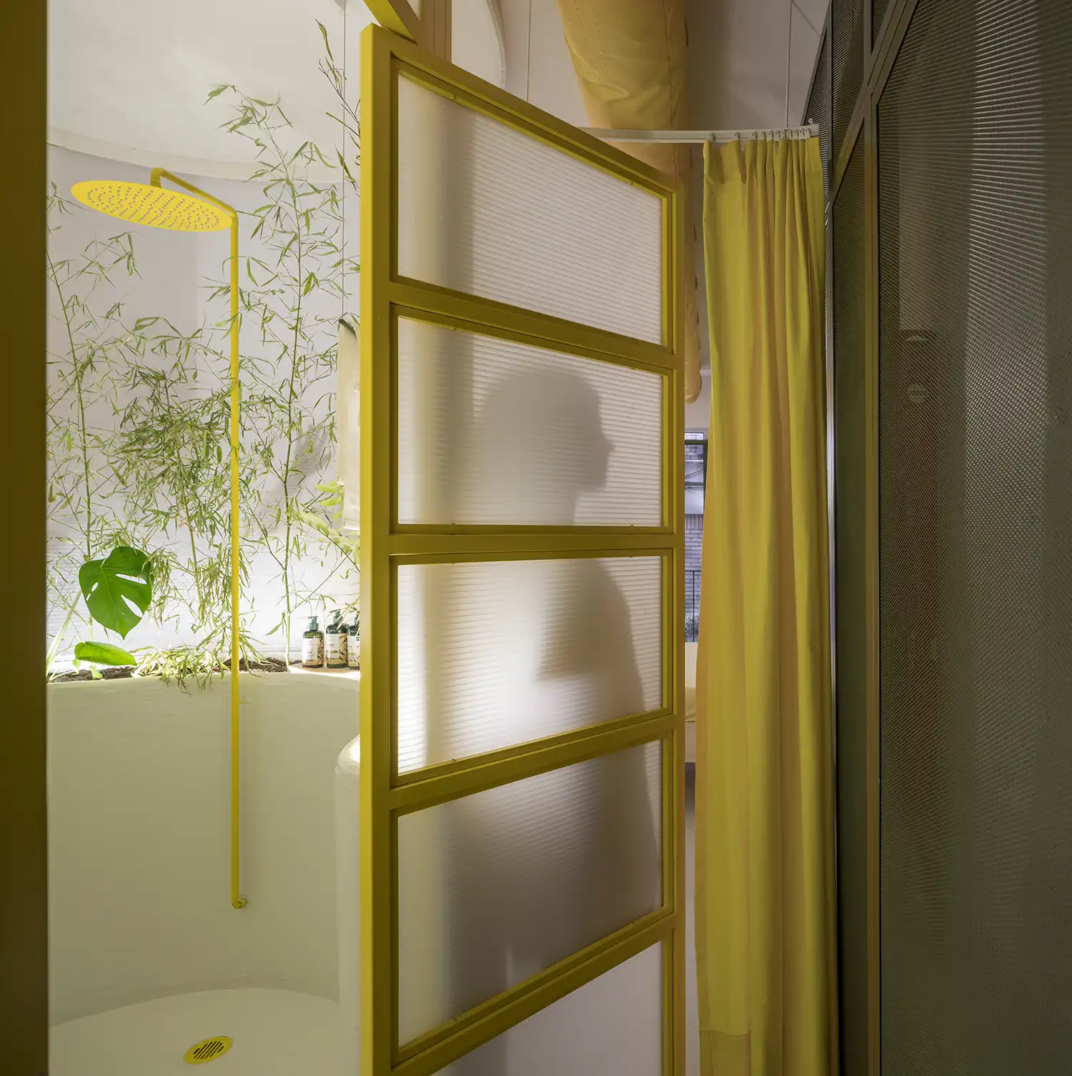 Translucent yellow-framed door leading to a shower with bamboo and a yellow showerhead.