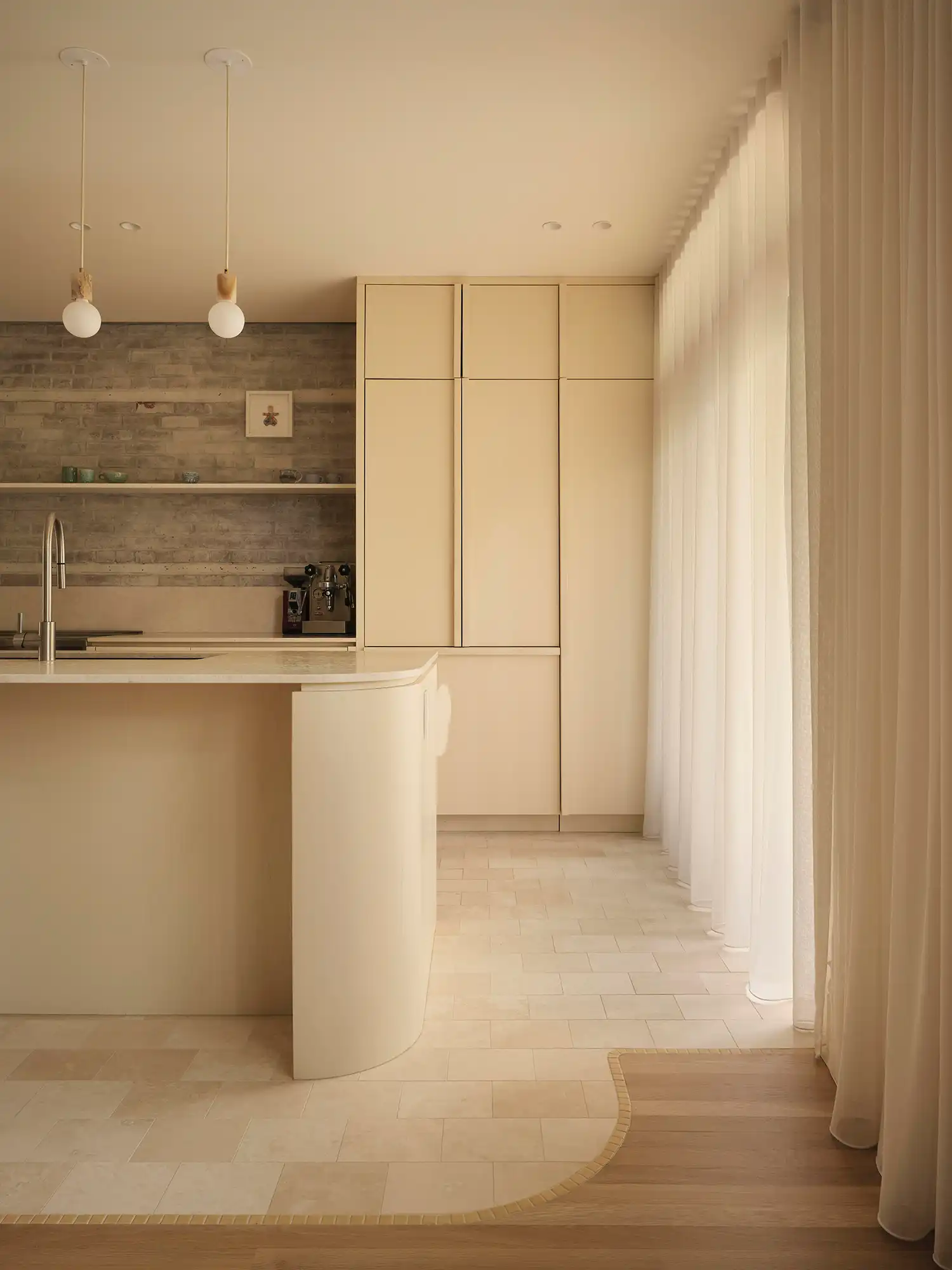 Soft "mayonnaise" tones and a curved island redefine the kitchen as a place of quiet, material dialogue.