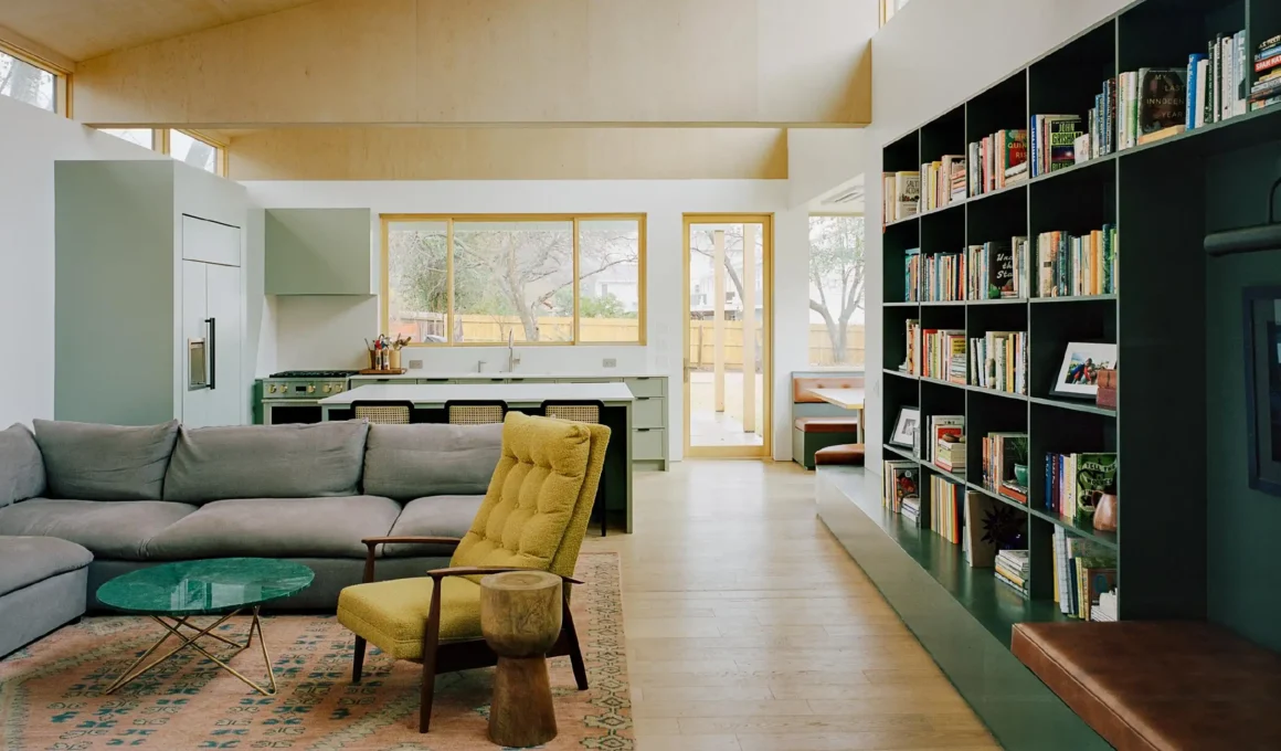 Open-plan living area with plywood coffered ceiling and green integrated shelving in Austin.