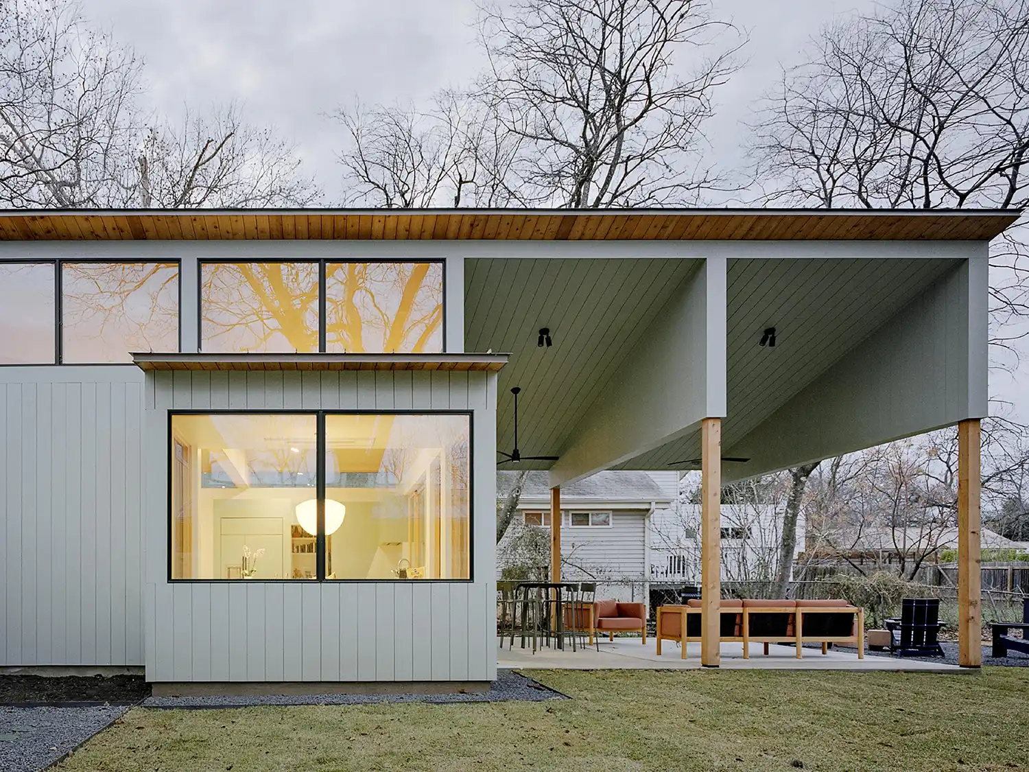 Geometric rear facade of the Coffered House at dusk with glowing interior lights.
